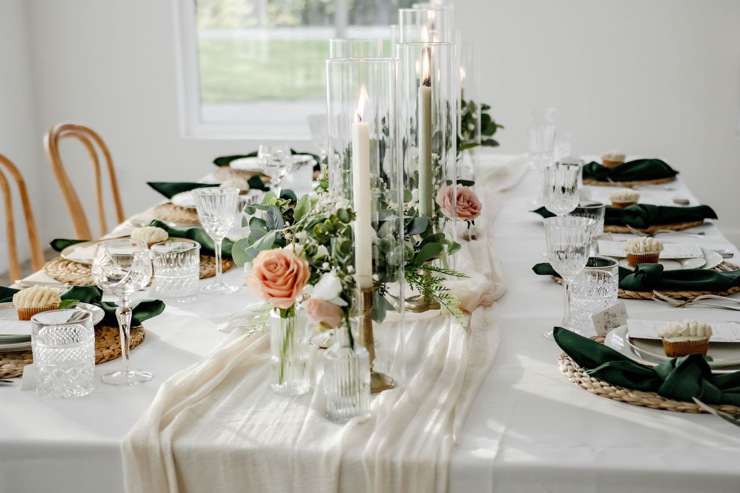 An elegant wedding table setting with tall candles, white linens, and floral centerpieces.