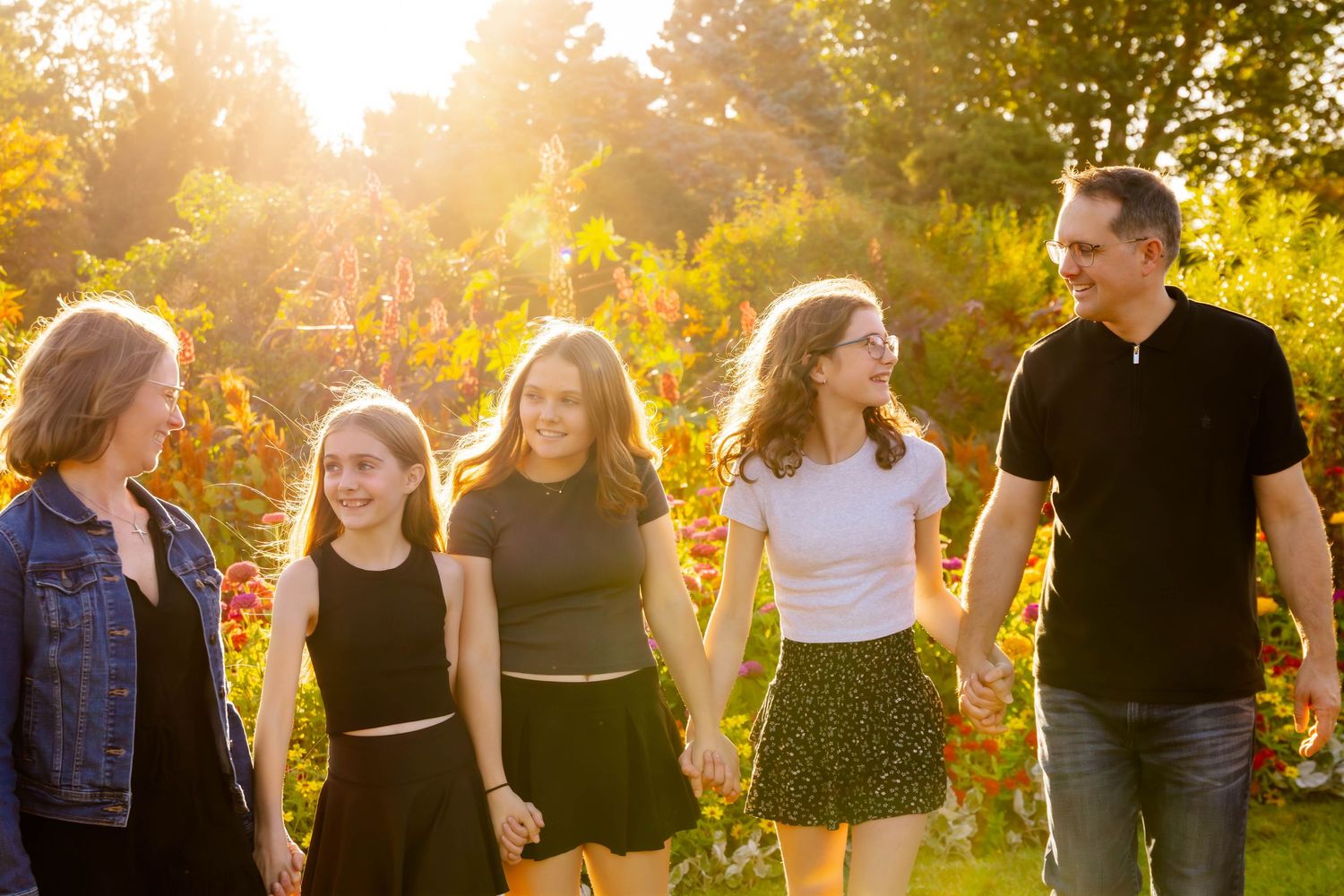 Family walking together through garden path with dramatic sunset backlighting.
