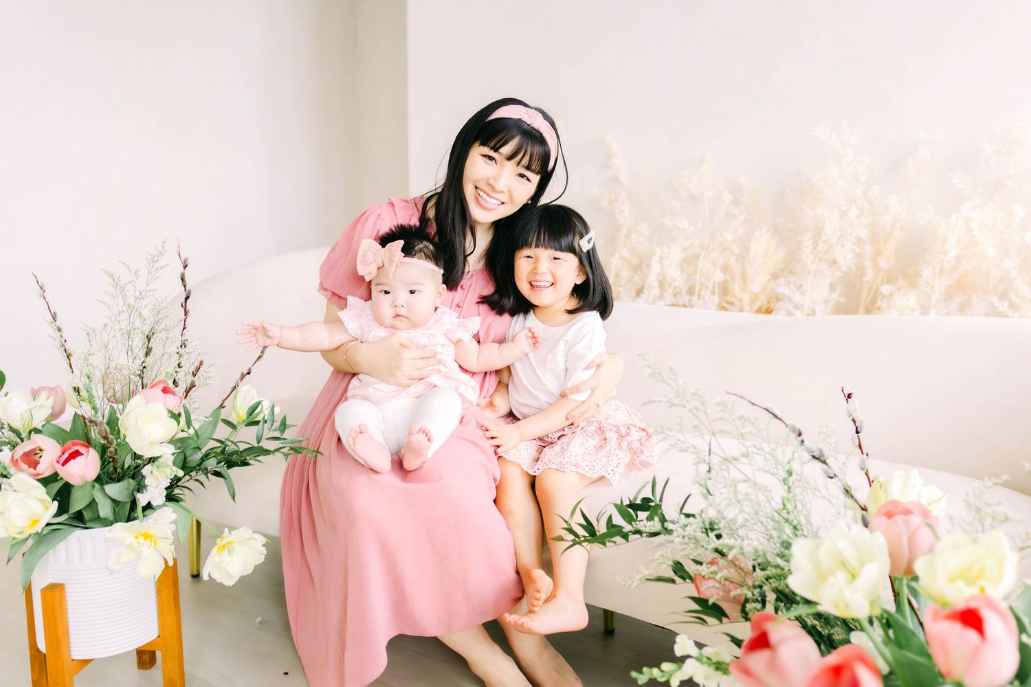 Family portrait in pink dresses surrounded by floral arrangements and pampas grass.