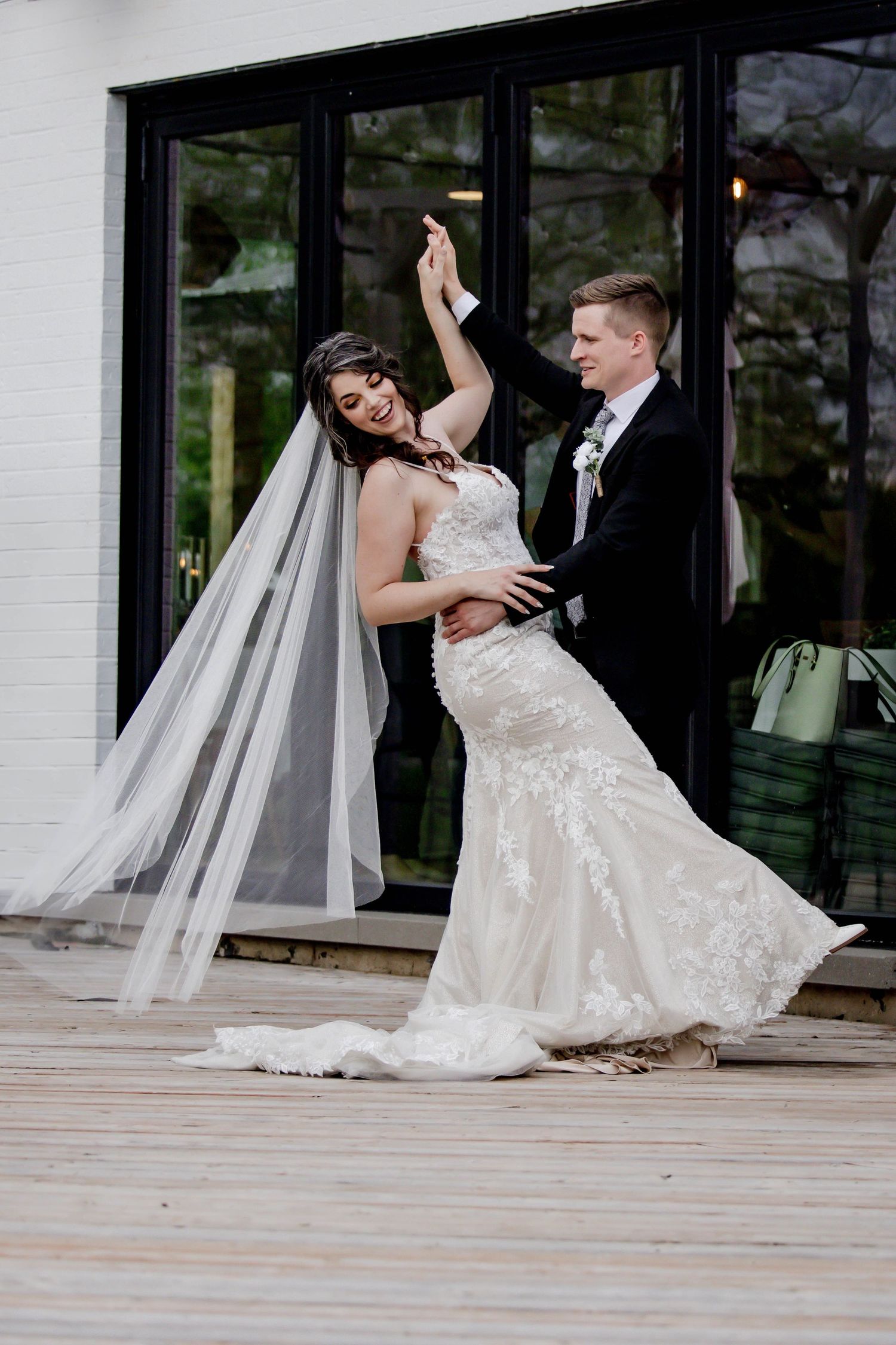 Couple shares a joyful dance moment on a wooden deck during their wedding celebration.