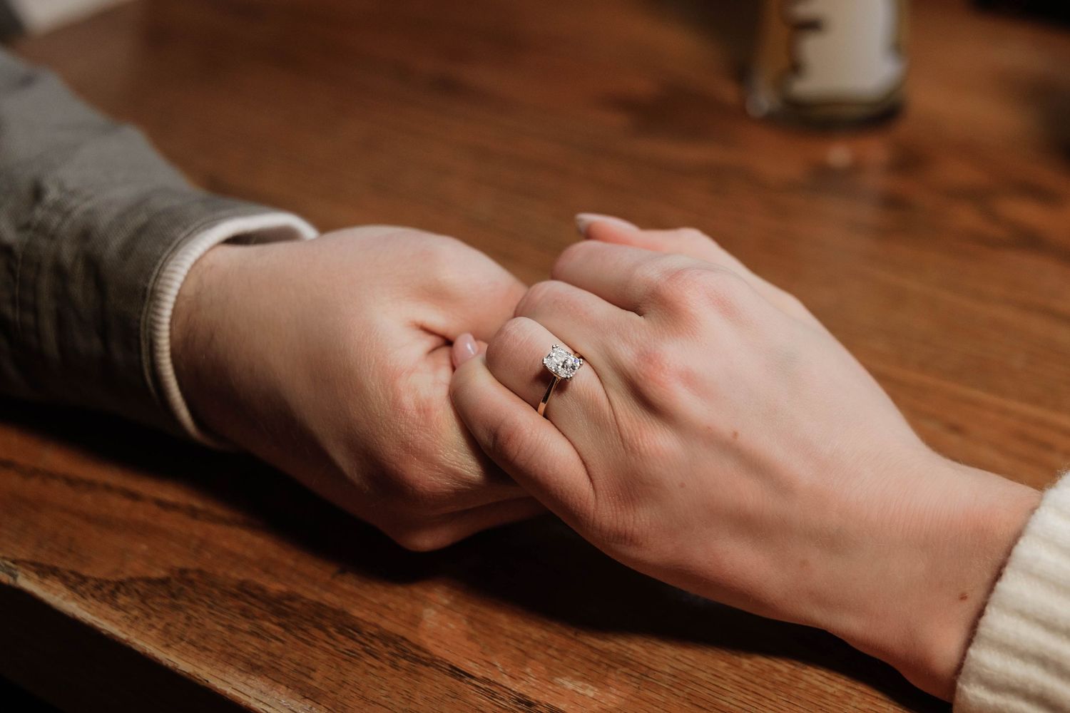 Close-up sequence showing hands with engagement ring on wooden table surface in warm lighting.