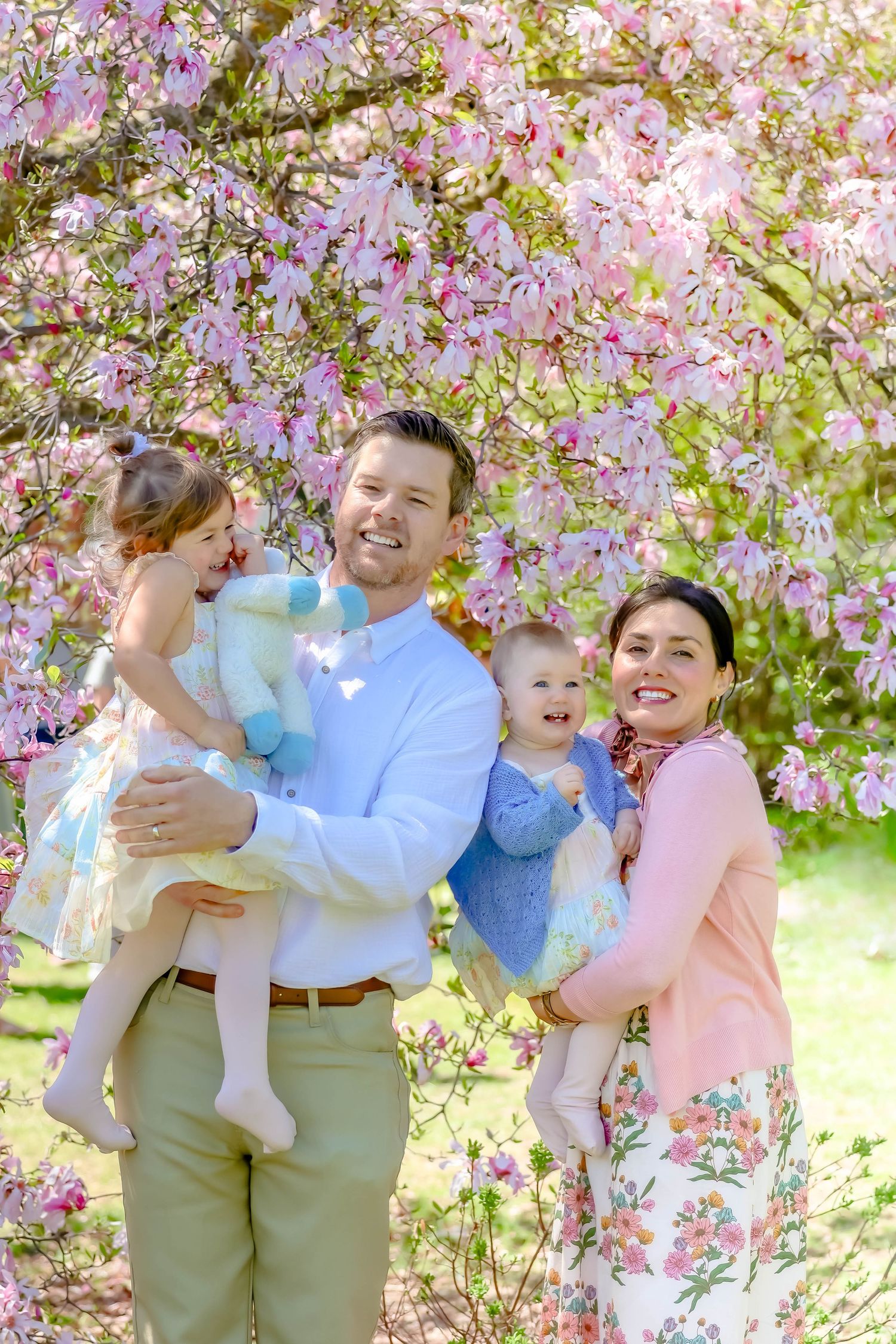 Family enjoying a playful moment beneath blooming cherry blossom trees.
