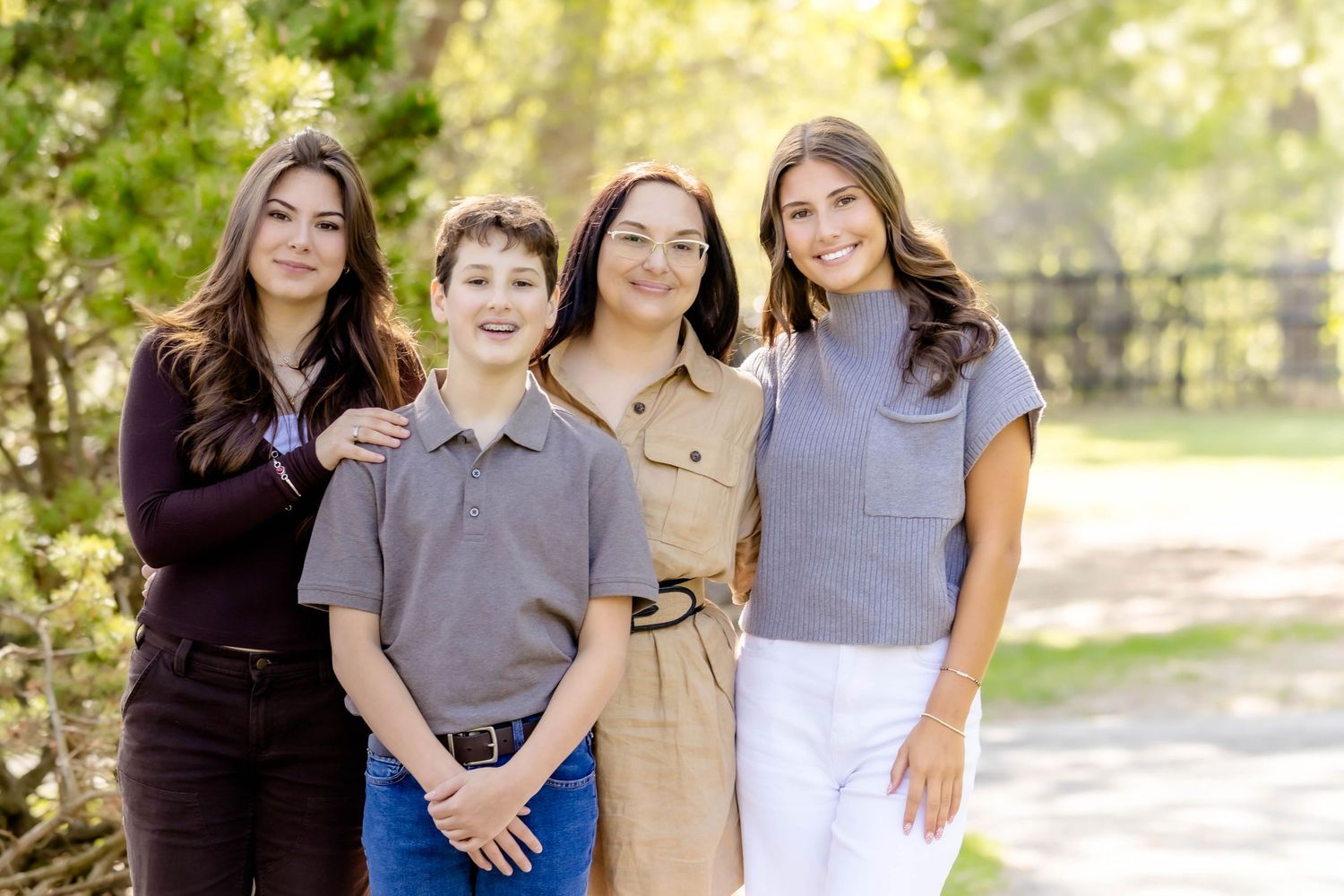 Family members pose together in coordinated outfits during a sunny outdoor photo session.
