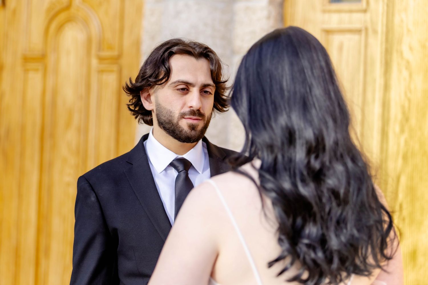 A couple shares a romantic moment during their wedding ceremony against a golden backdrop.
