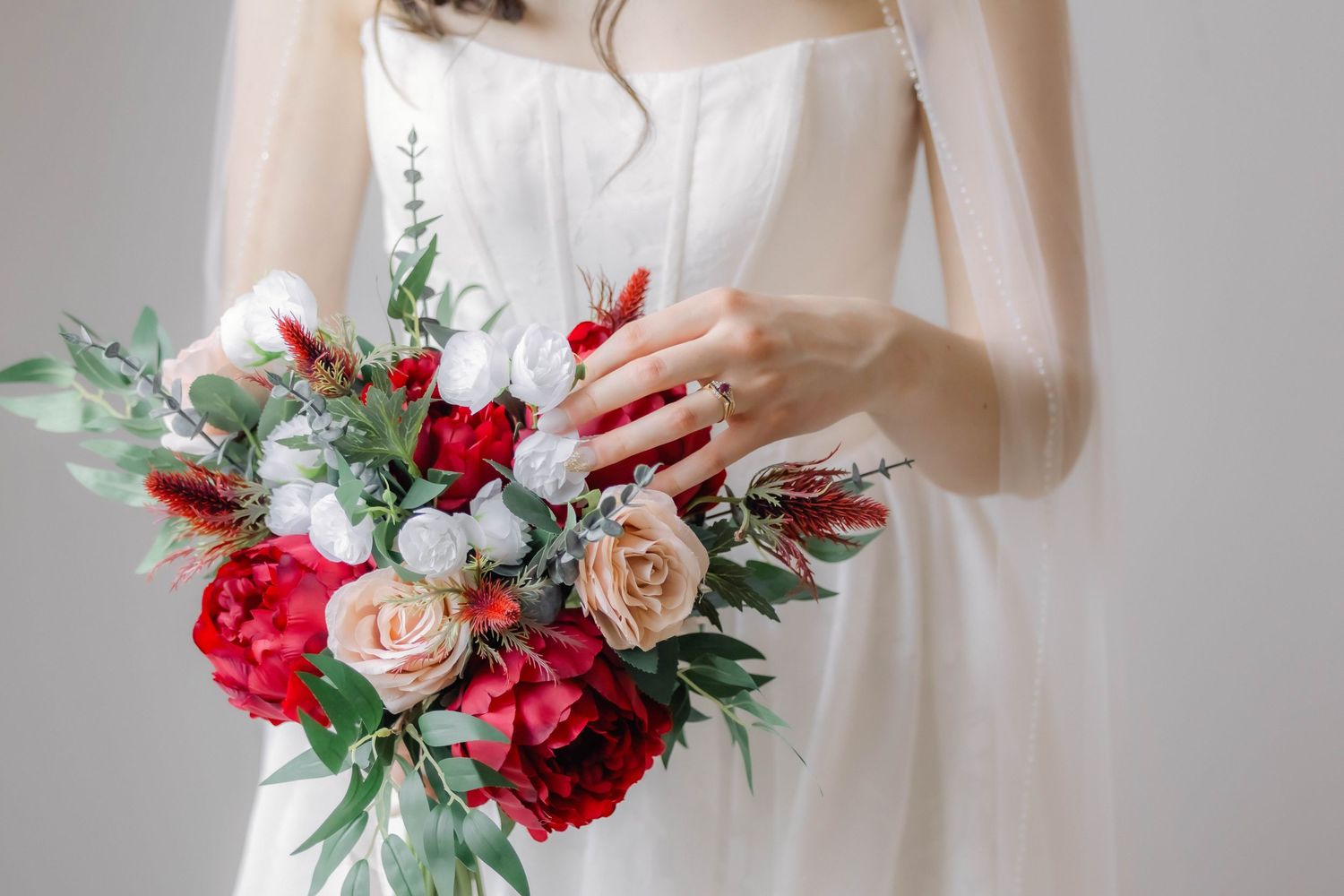 Beautiful wedding bouquet featuring deep red and blush pink roses with greenery accents.