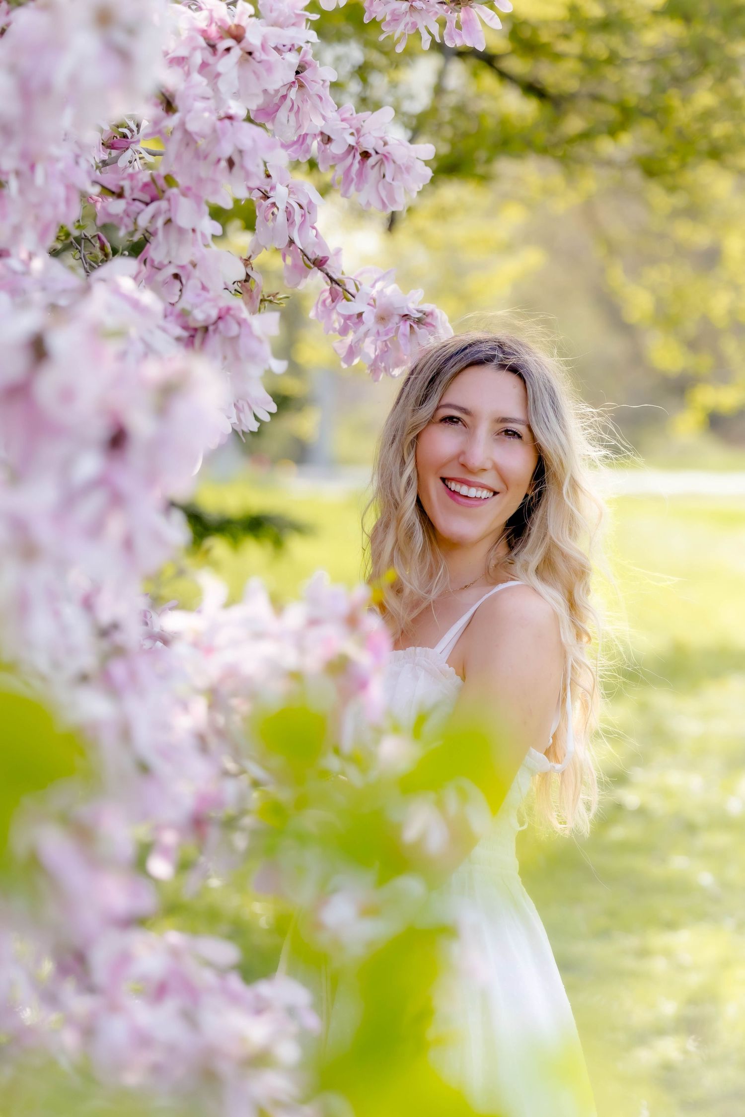 Spring portrait among blooming cherry blossoms in soft natural lighting.