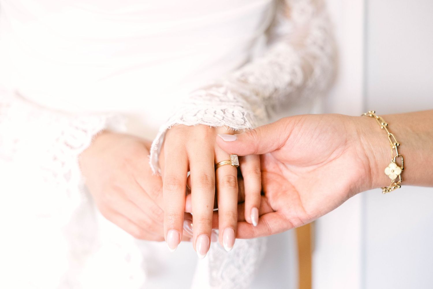 Close-up of bride's hands with engagement ring and gold bracelet during wedding preparation.