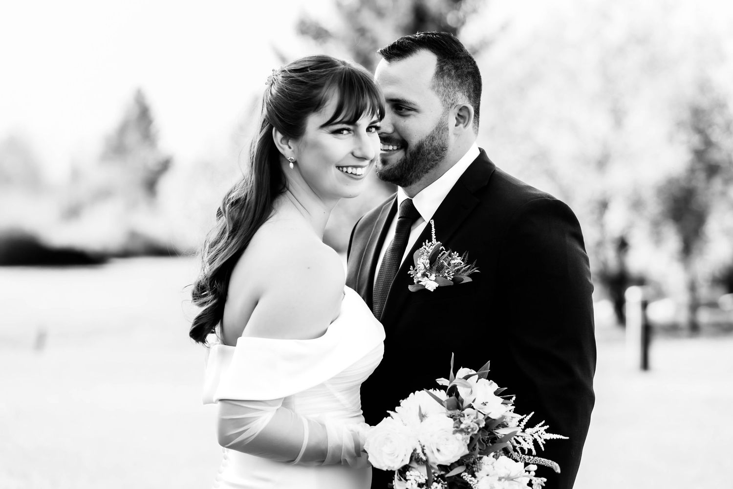 Black and white portrait of newlyweds sharing romantic moments outdoors.