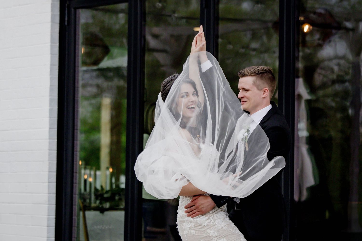 Elegant wedding dance sequence captured against black-framed windows.