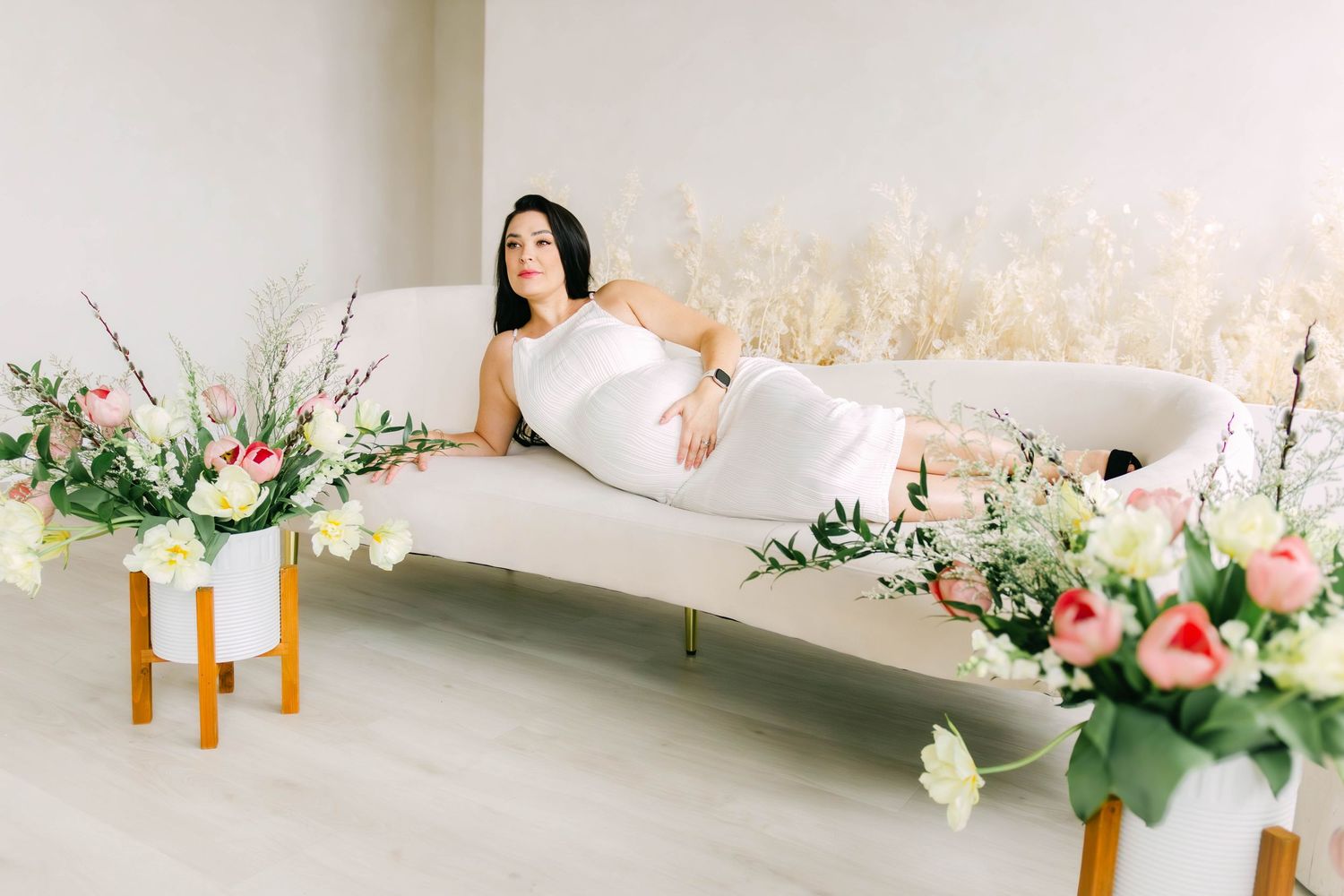 Elegant studio setup with floral arrangements and soft white backdrop.