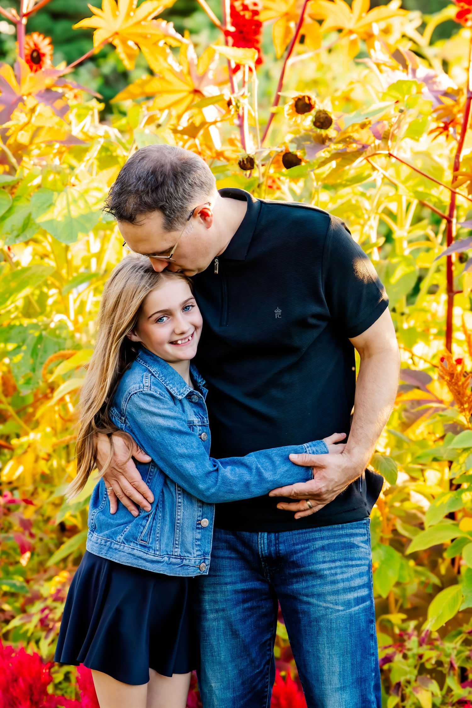 Candid moments captured in a garden setting with sunflowers and red plants in the background.
