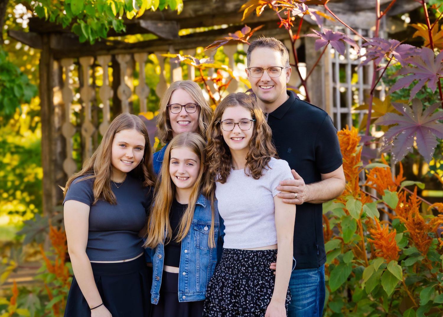 Family members posing together in lush garden setting with warm evening light.