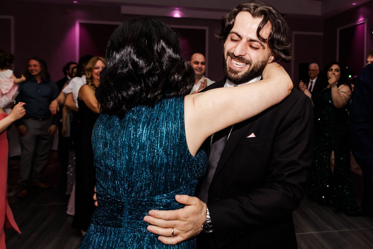 Couple dancing together at a wedding reception with purple lighting and a festive atmosphere.
