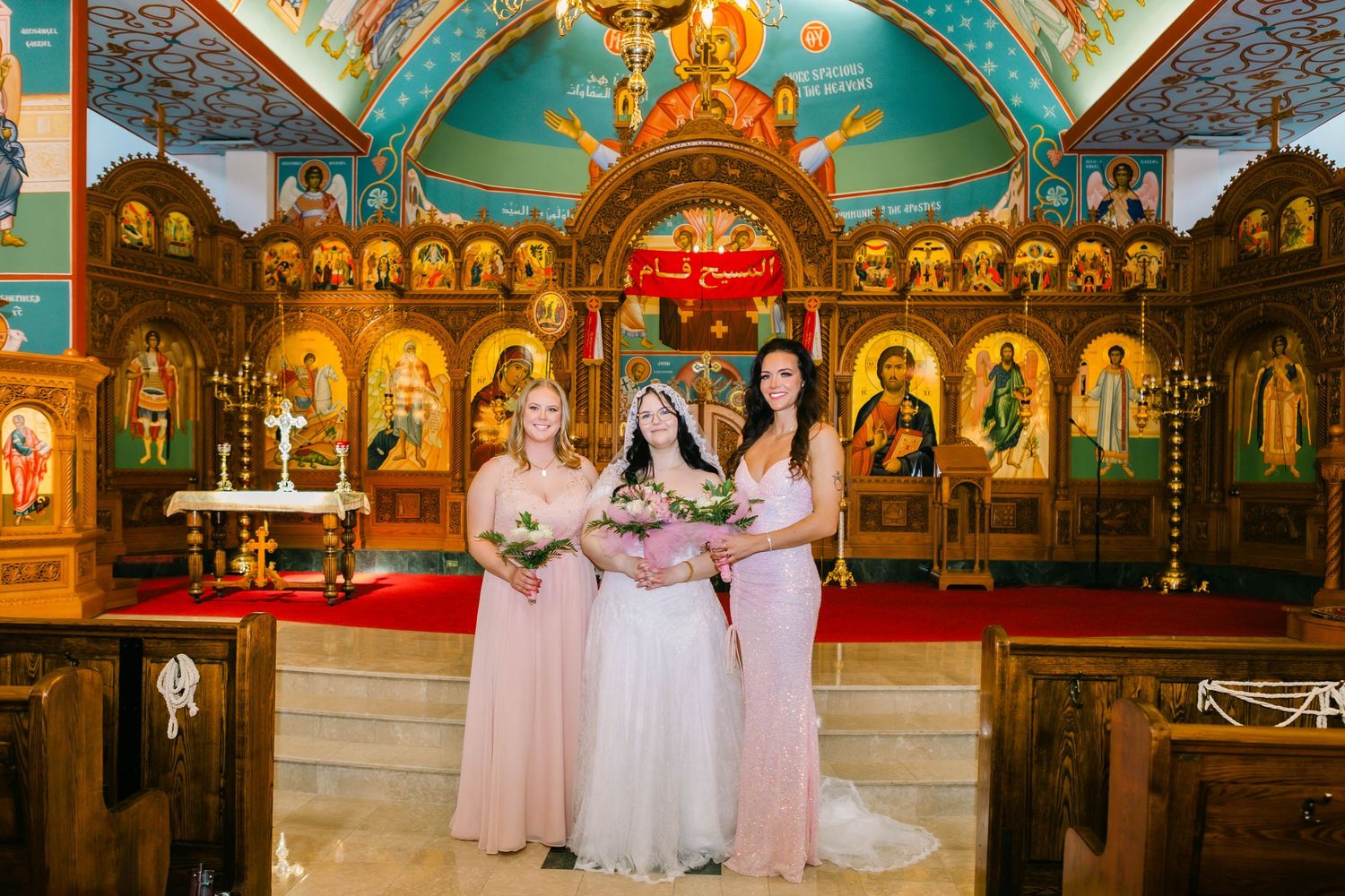 Interior of Orthodox church with turquoise ceiling and golden iconostasis during wedding ceremony.