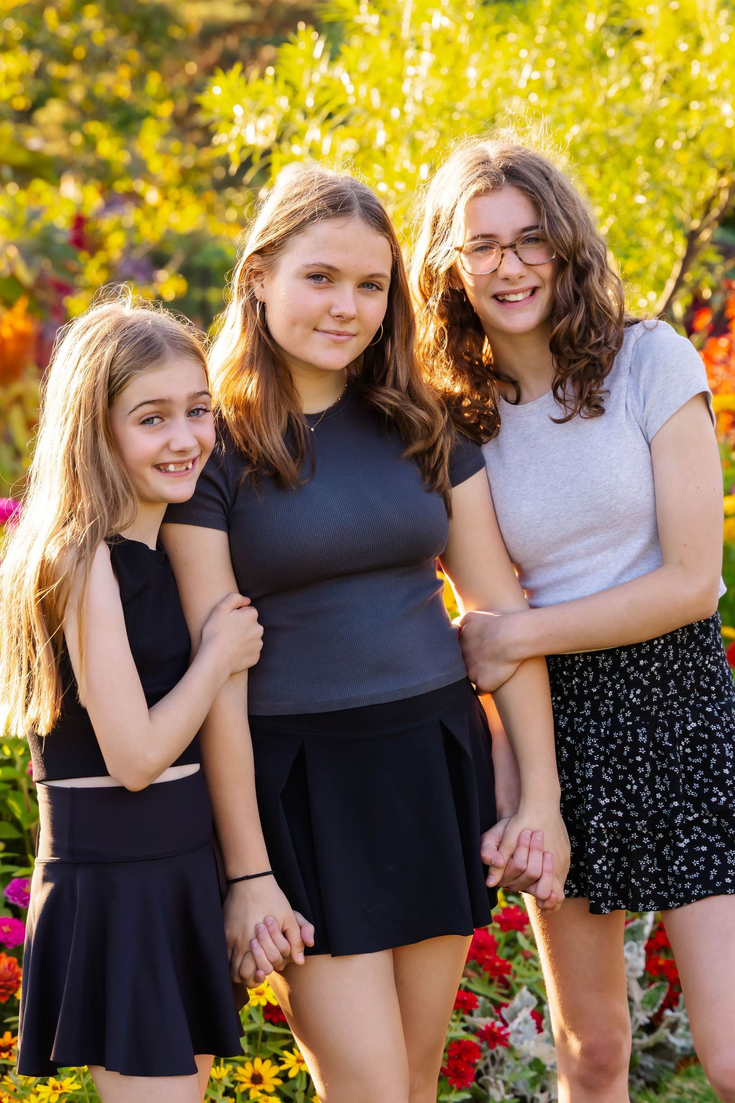 A casual group photo in a garden with people wearing black outfits against golden fall foliage.