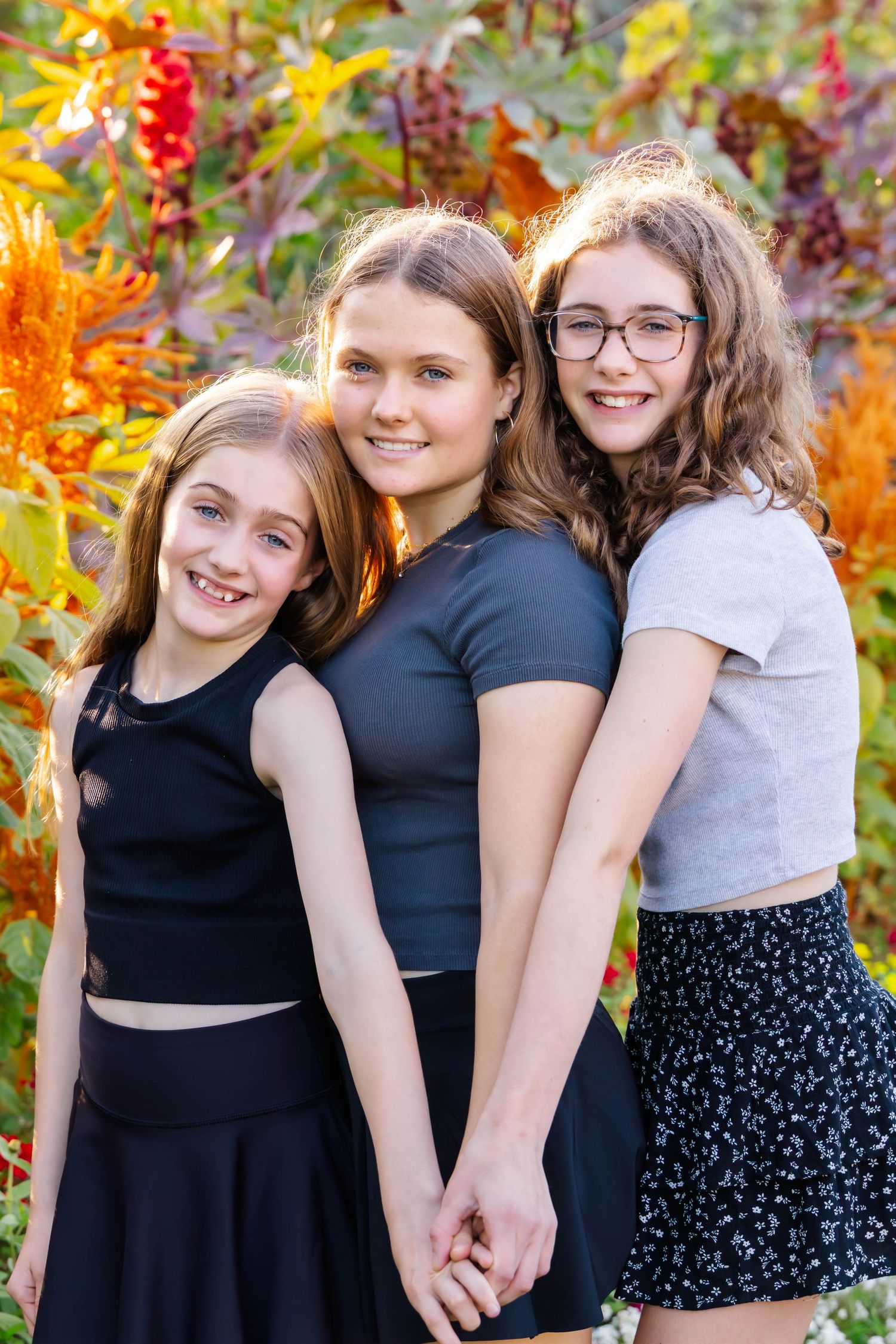 Group photo series in black outfits against a backdrop of autumn flowers and foliage.