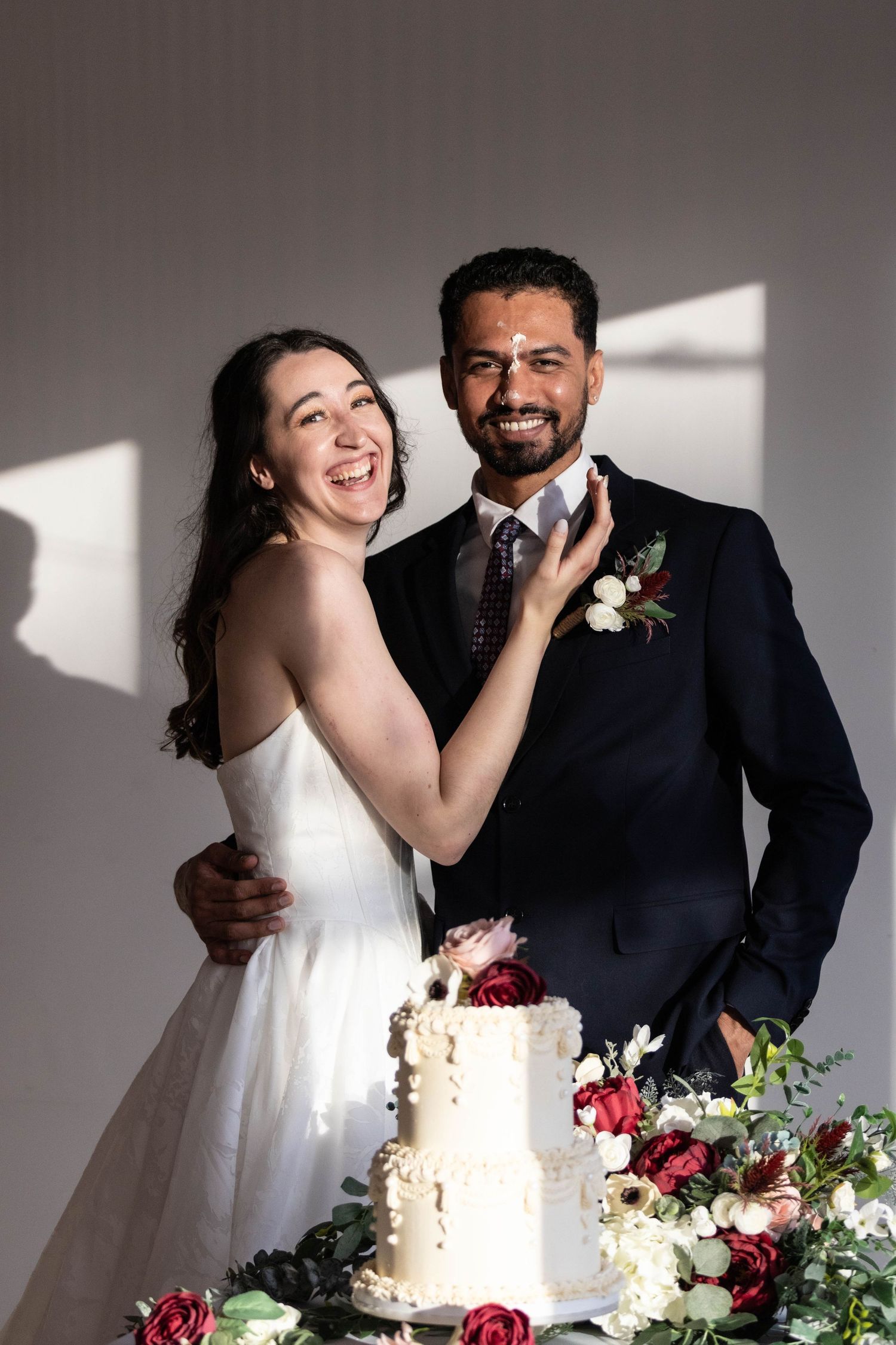 Wedding celebration scene with a white tiered cake decorated with fresh flowers.
