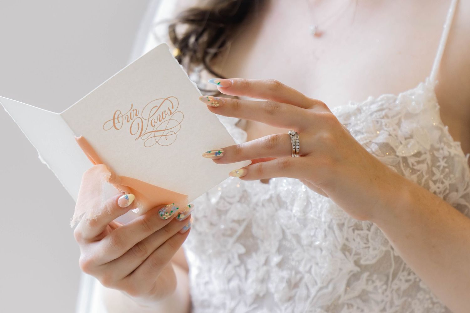 Delicate white lace details and wedding rings displayed on elegant stationery.