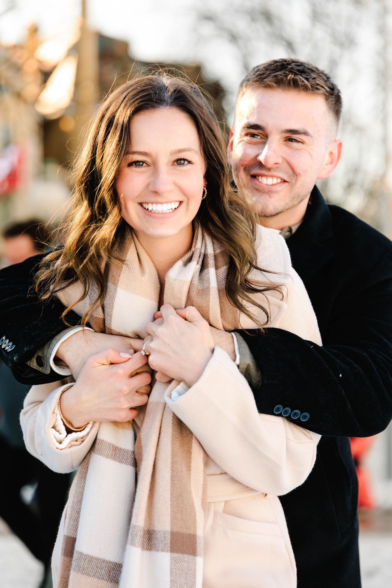 A couple shares joyful laughter and embraces while wearing winter attire outdoors in a romantic photoshoot series.