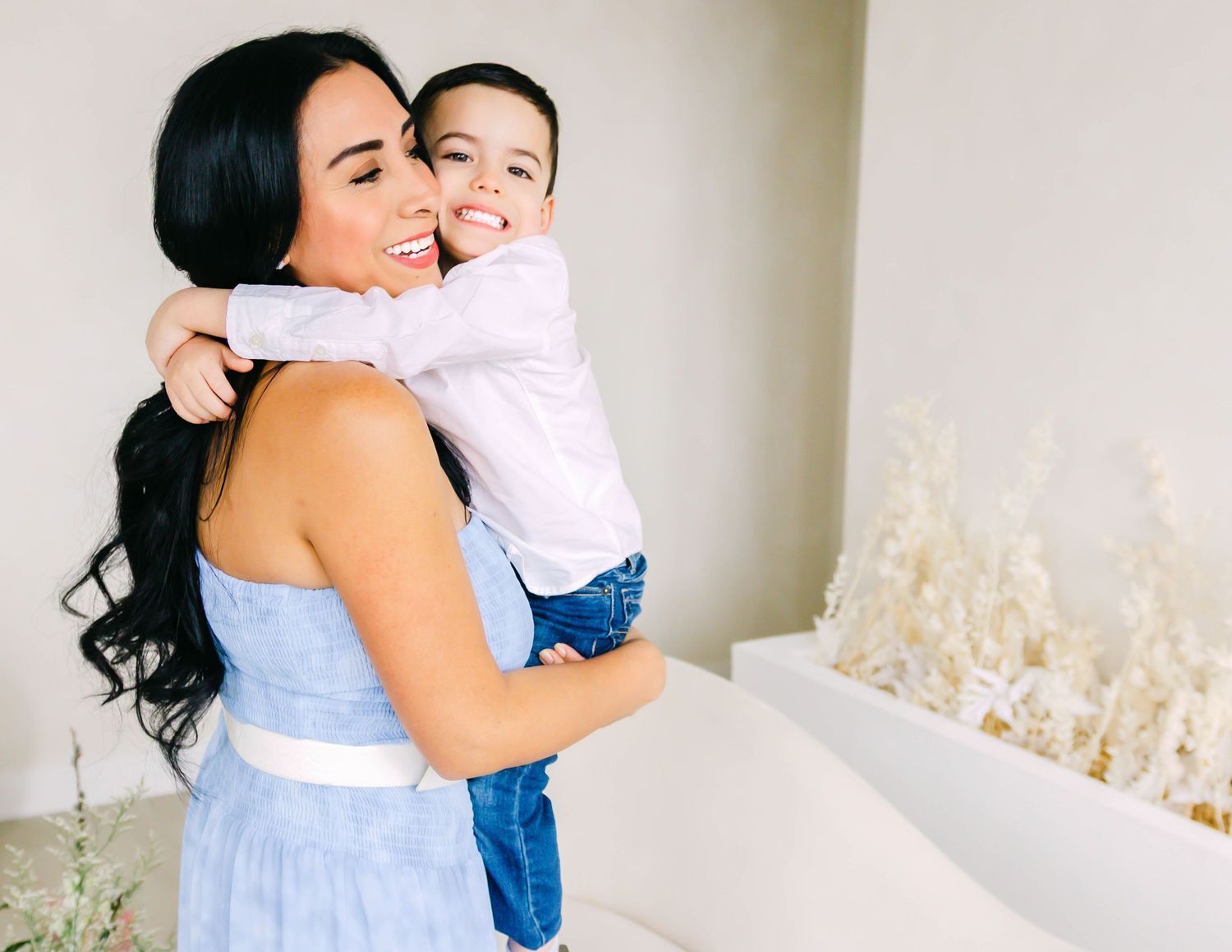 A heartwarming sequence of photos shows a mother and child embracing in a light-filled room with white floral decor.