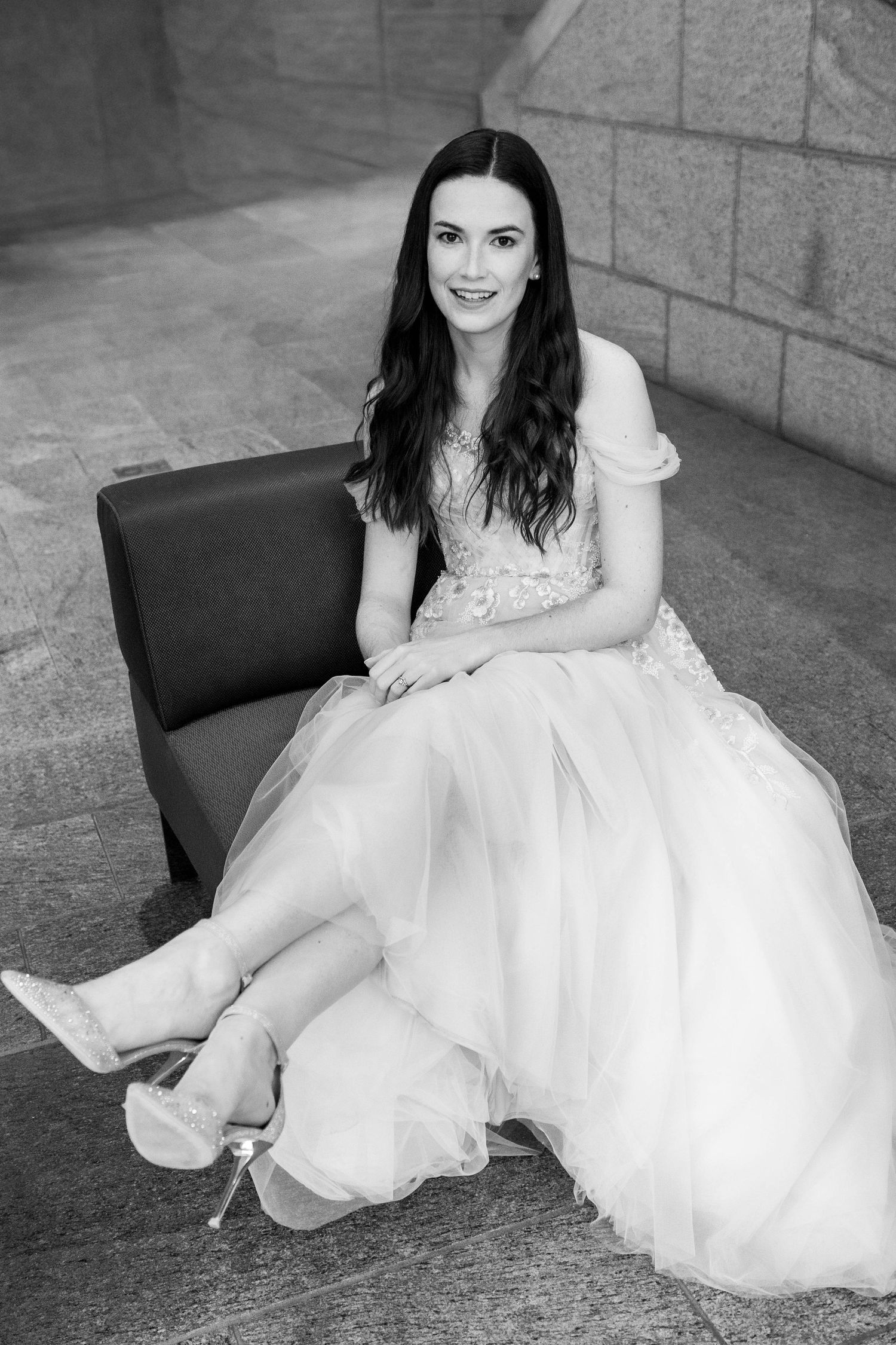 Black and white photo series showing details of a bride in a white dress sitting on a dark chair against a stone wall.