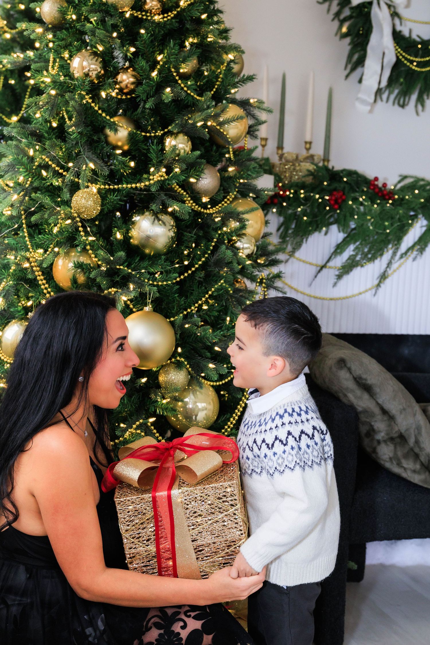 Holiday photo session with Christmas tree and wrapped presents in background.