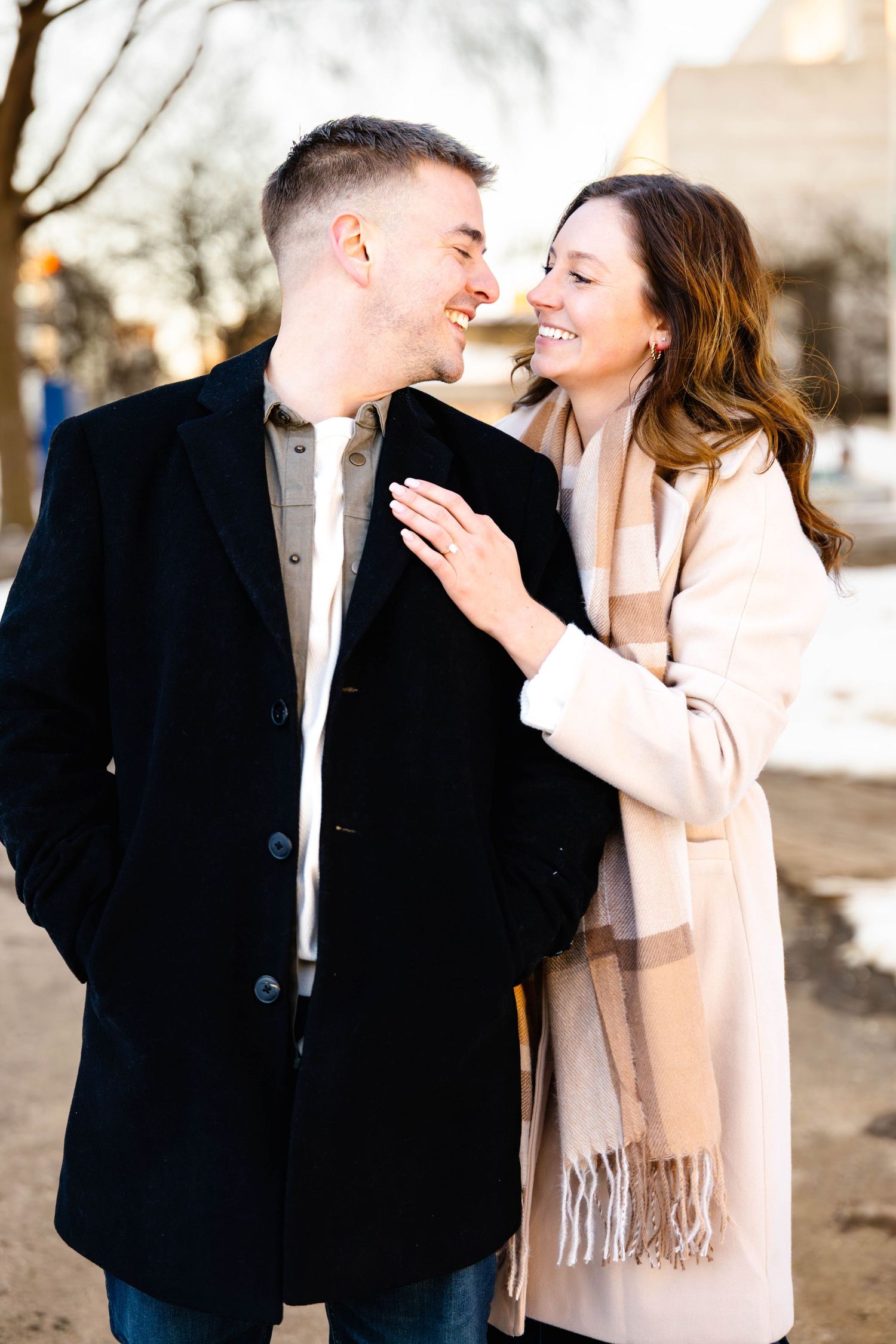 A romantic couple shares tender moments in a winter engagement photo session wearing black and beige outfits.