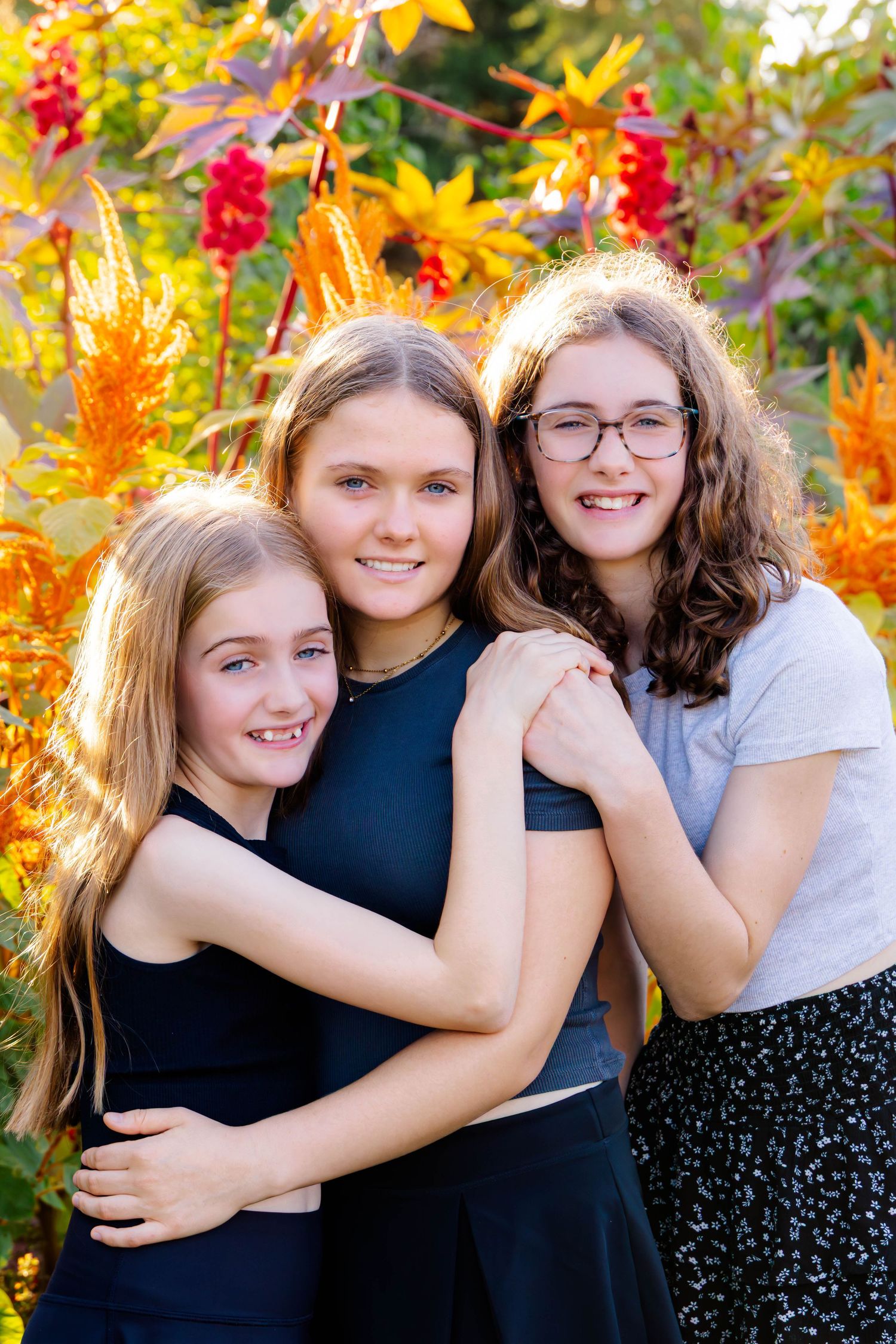 A group embraces while posing in front of bright yellow and red fall foliage during a photo session.