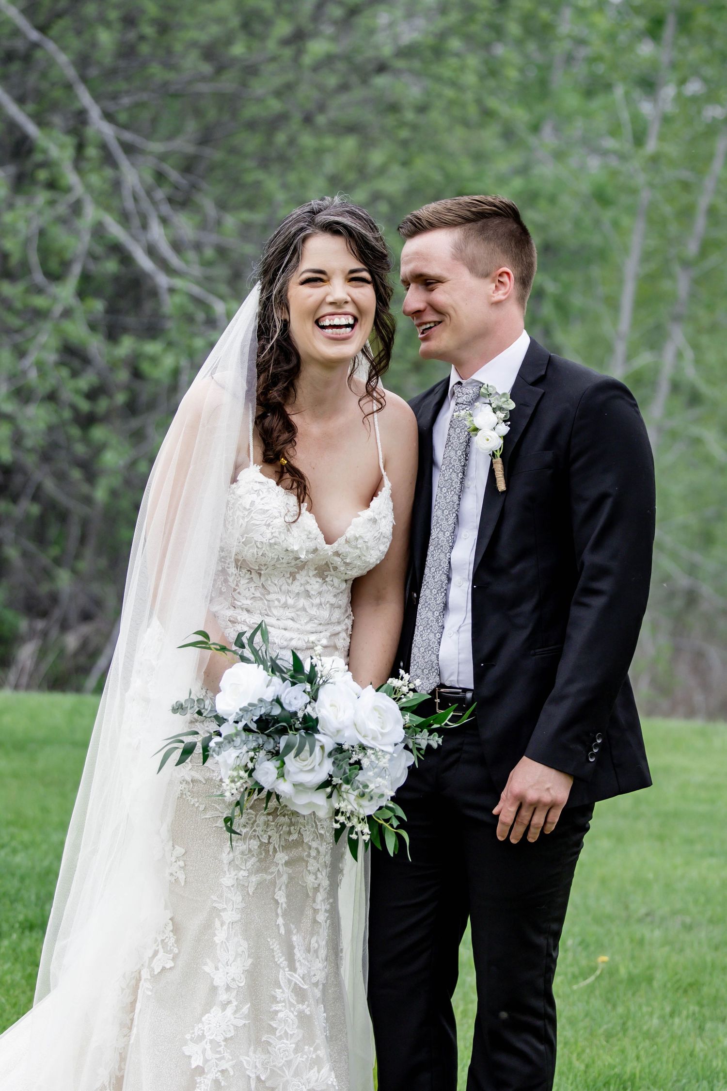 Newlyweds share joyful moments in a lush outdoor garden setting with white floral bouquet.