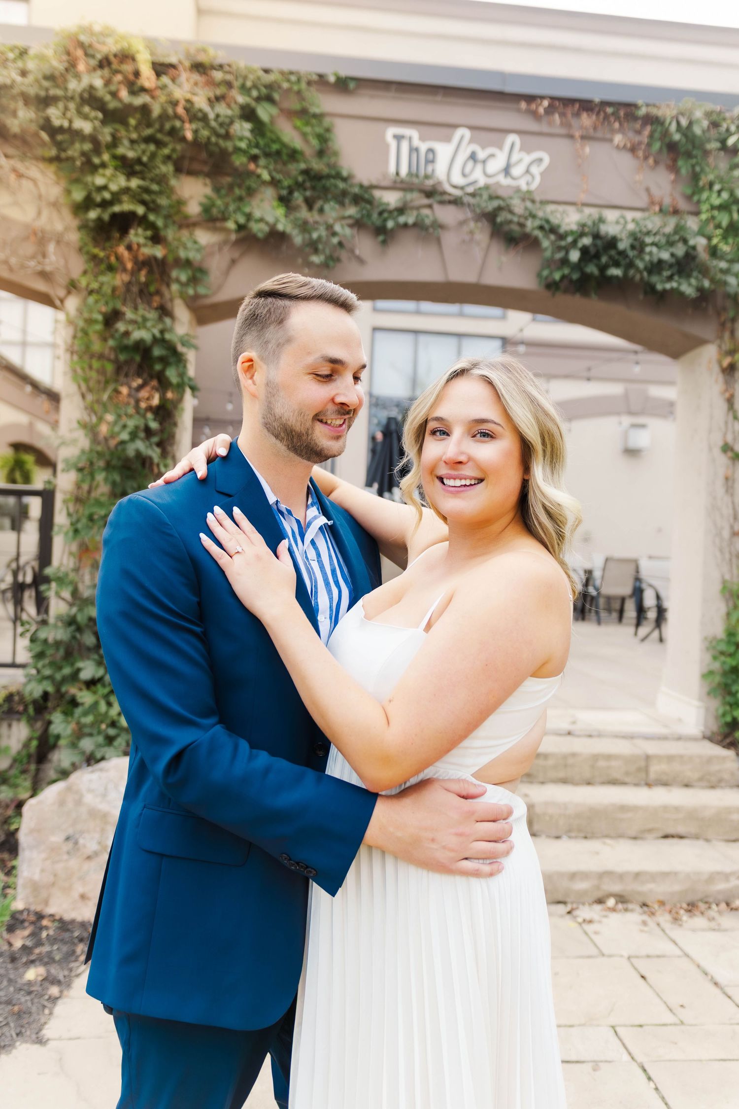 Happy couple shares intimate moment against stone wall with climbing vines.