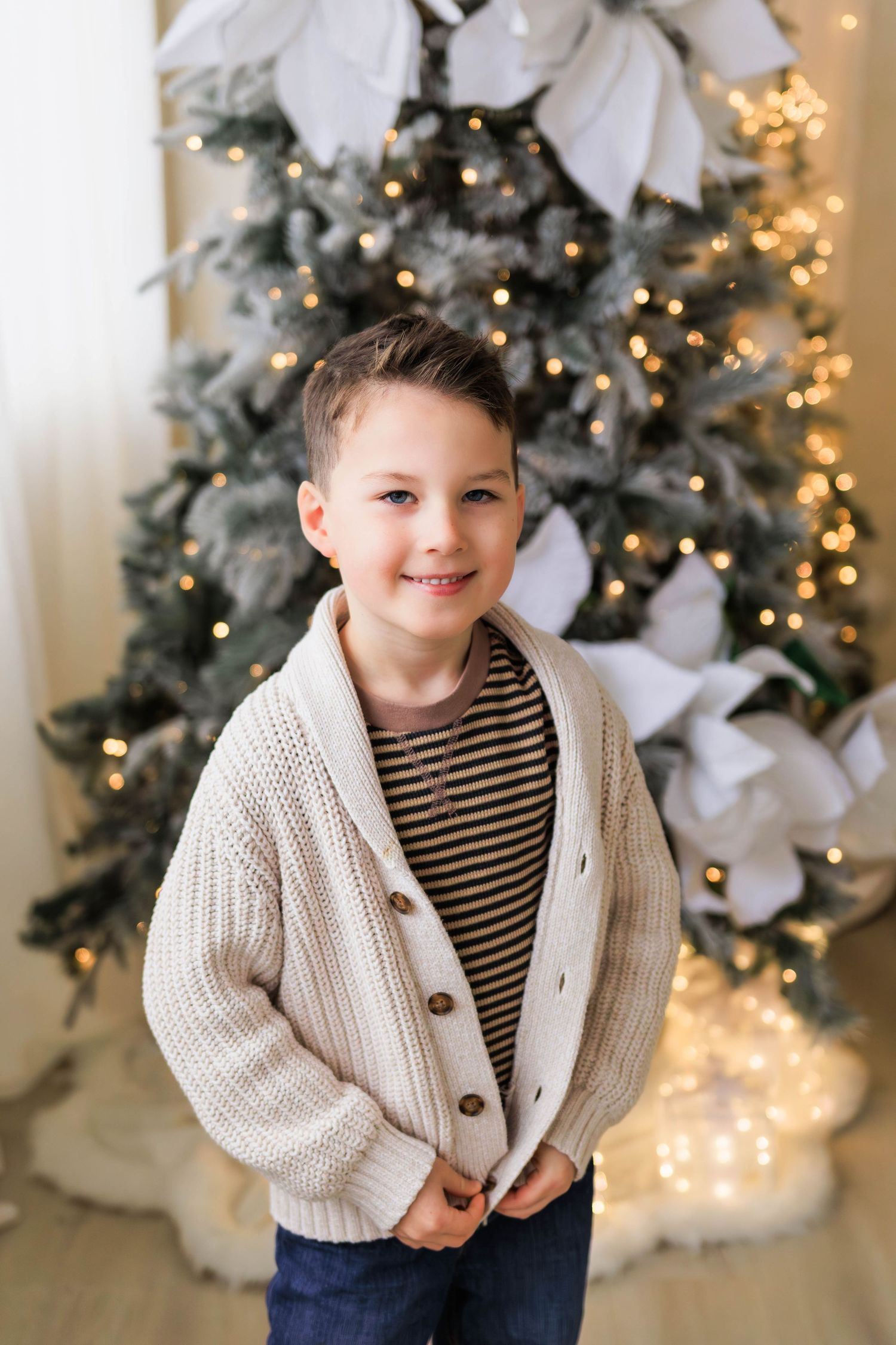 Winter portrait against a decorated Christmas tree with white ornaments and twinkling lights.