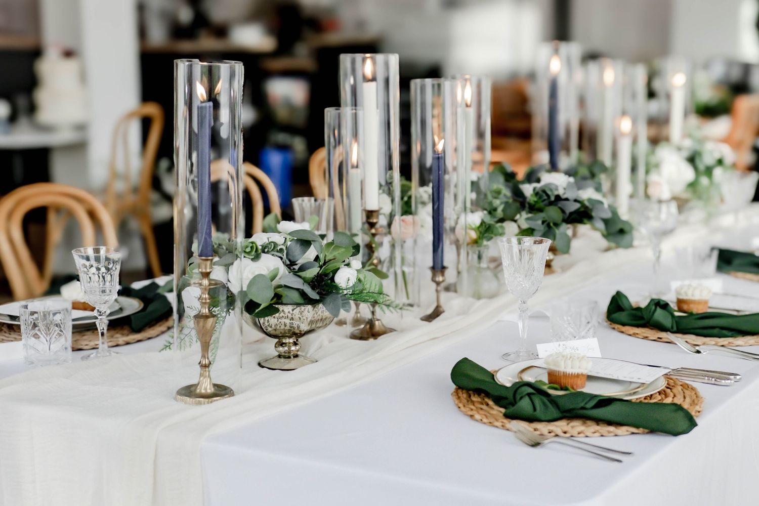 Wedding reception table with emerald green napkins and crystal stemware in natural lighting.