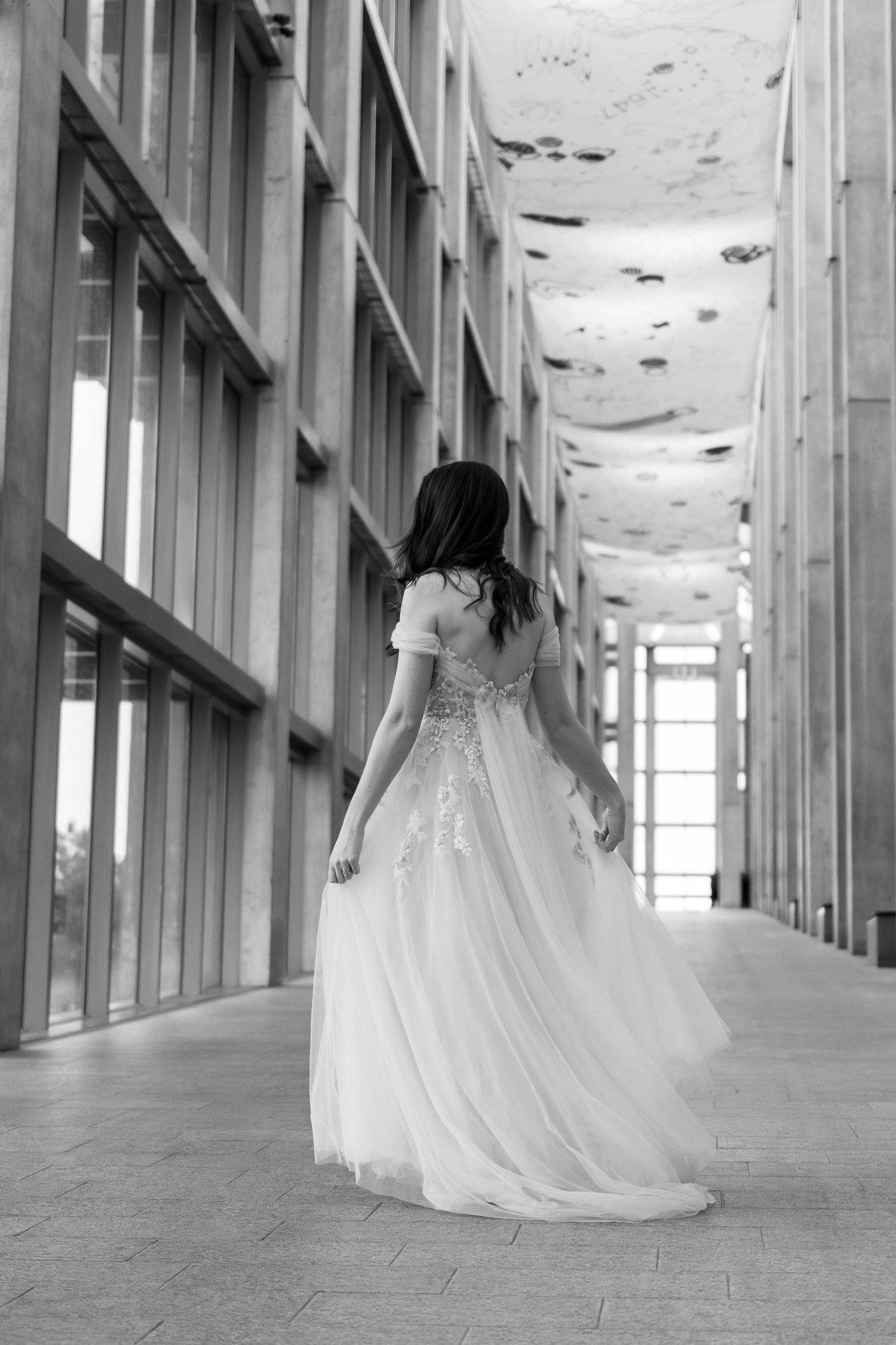 A black and white photo series shows a person in a flowing wedding dress walking through an elegant hallway.