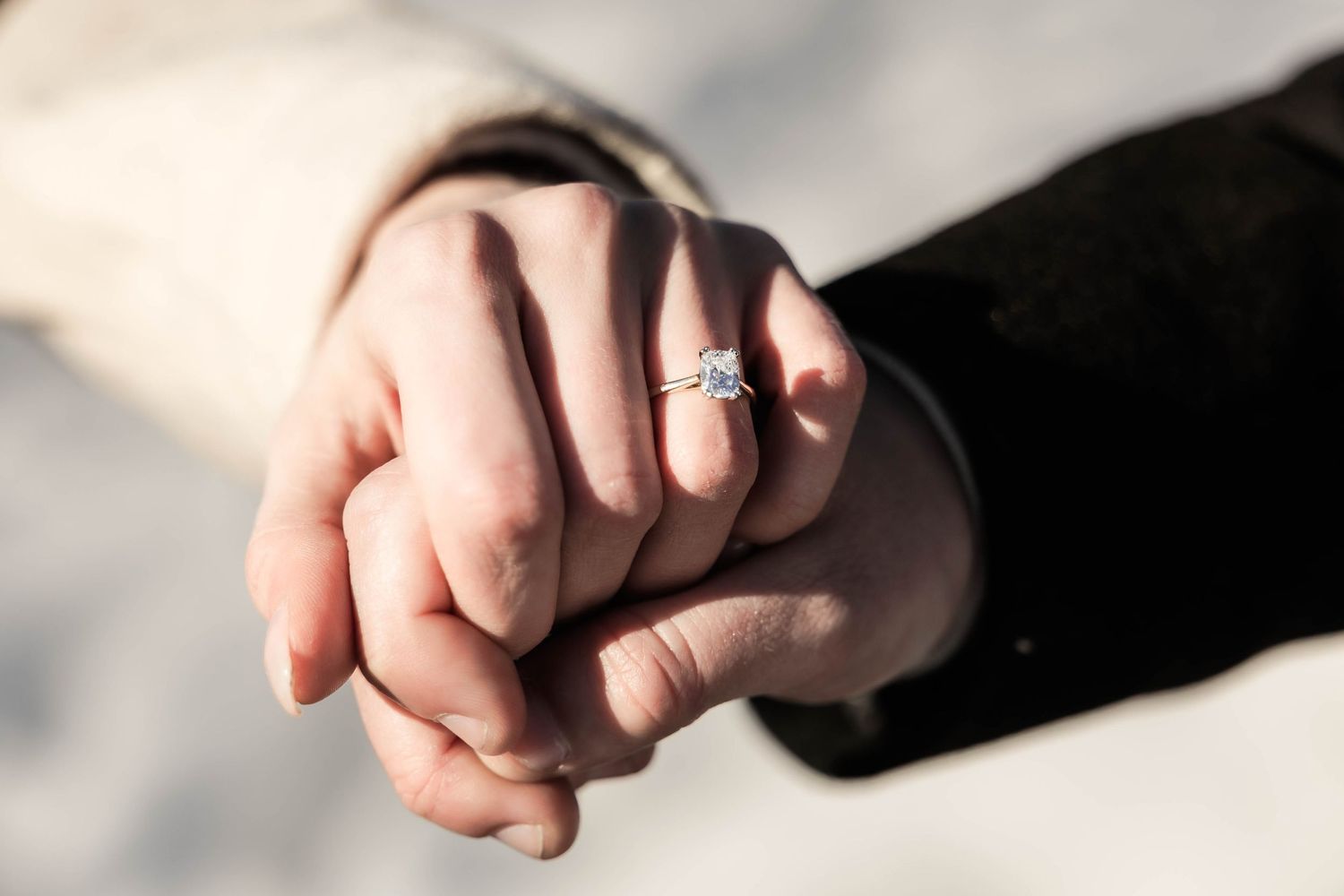 Close-up view of hands wearing wedding rings against a soft white background.