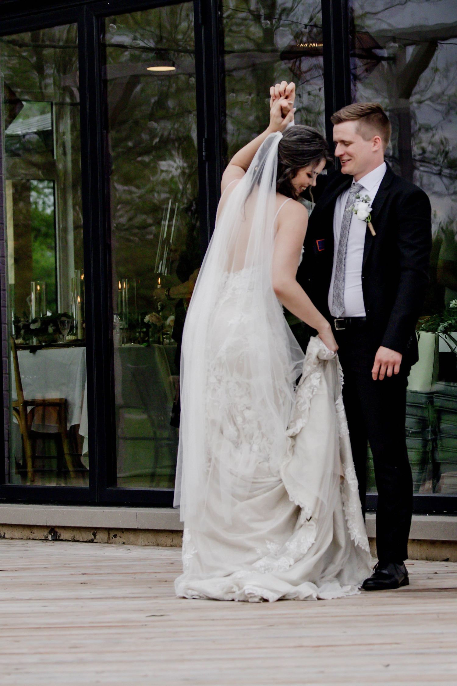 Wedding couple creates dynamic movement shots on outdoor deck with glass backdrop.