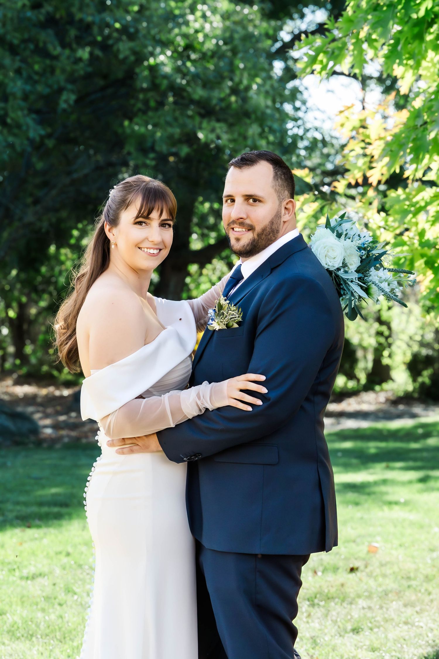 A couple shares a joyful moment together in a garden setting during their wedding photoshoot.