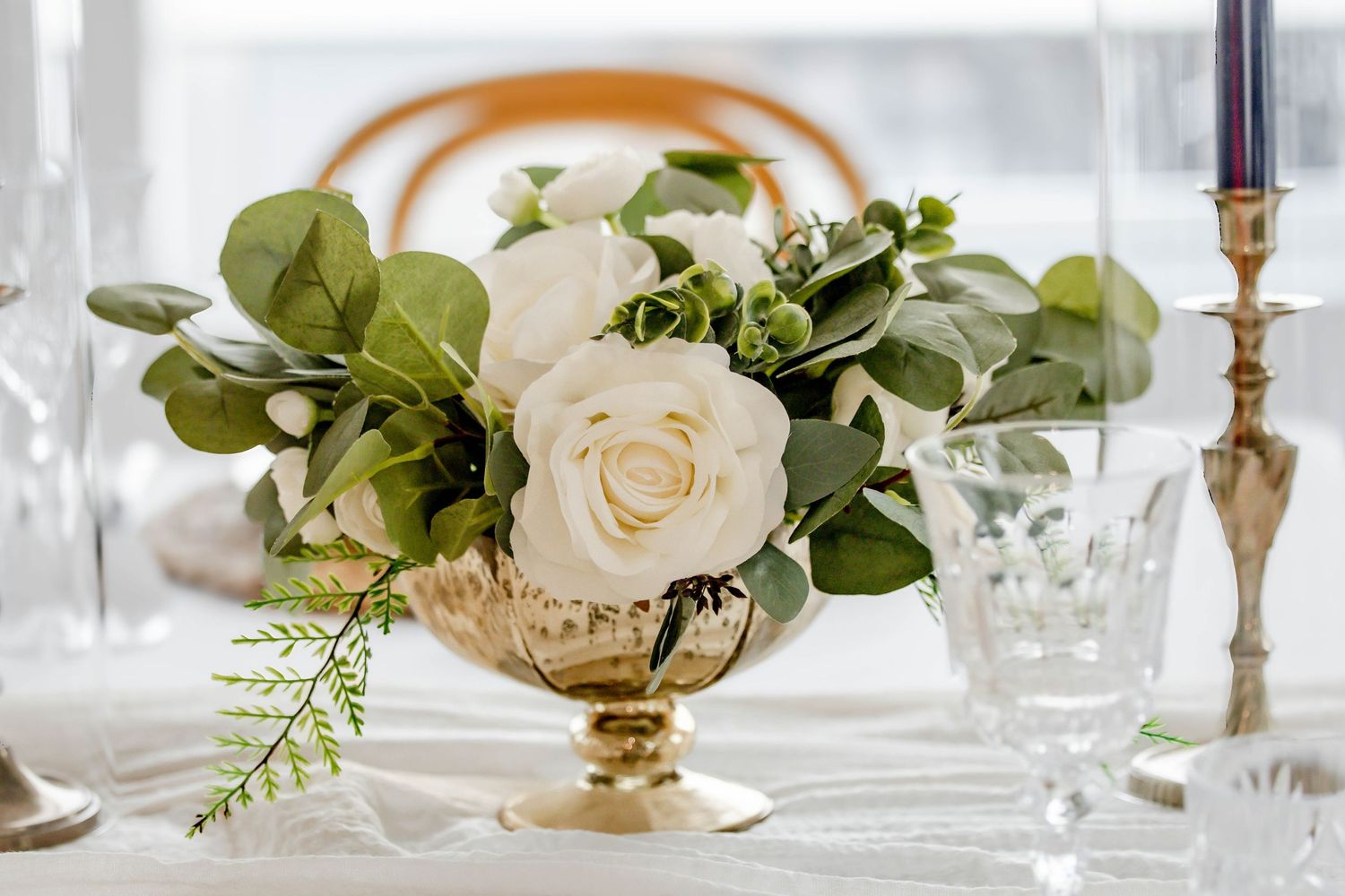 Elegant table setting with white roses, gold candlesticks and crystal glassware.