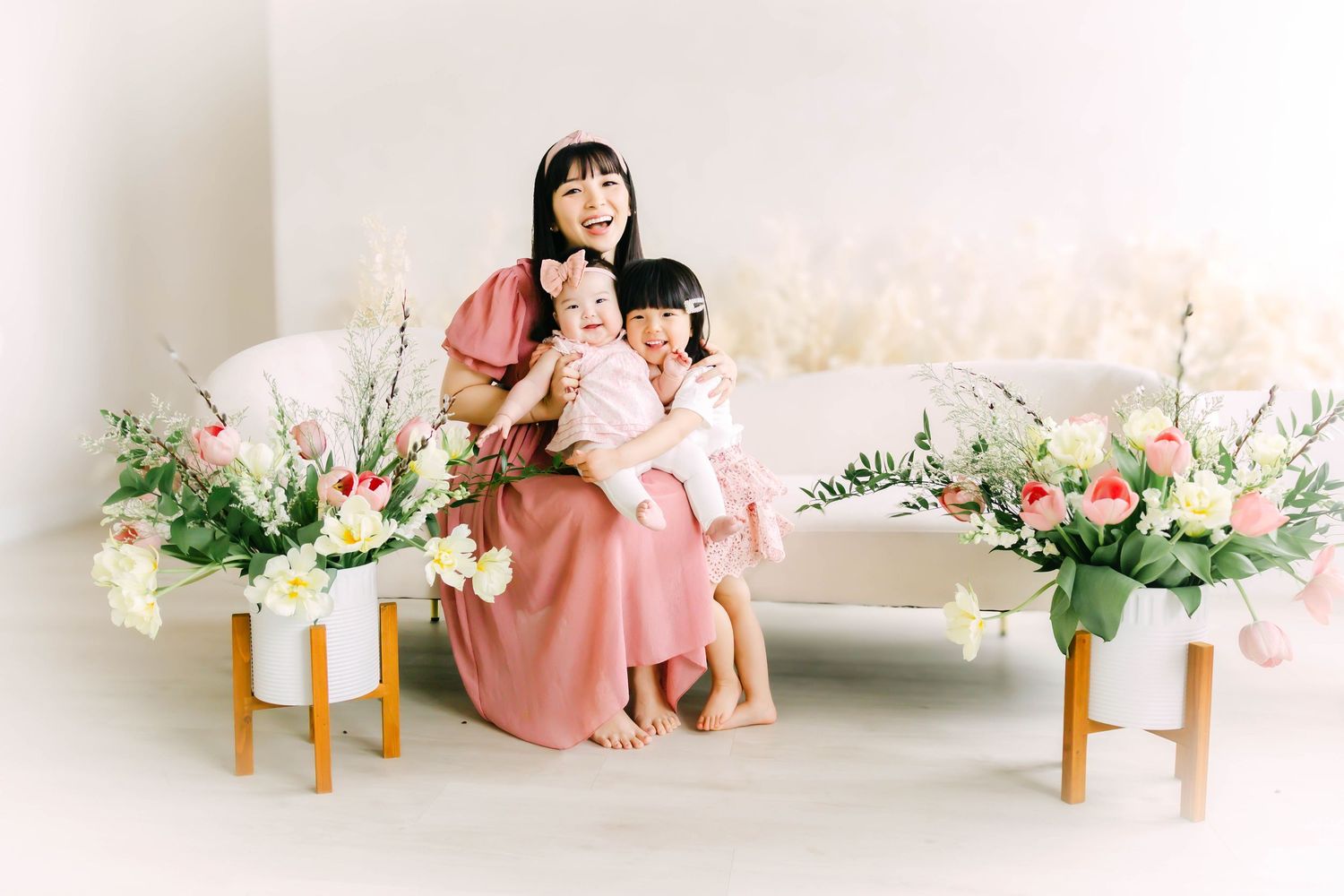 A series of soft pink and white floral photography set designs with wooden stools and delicate arrangements.