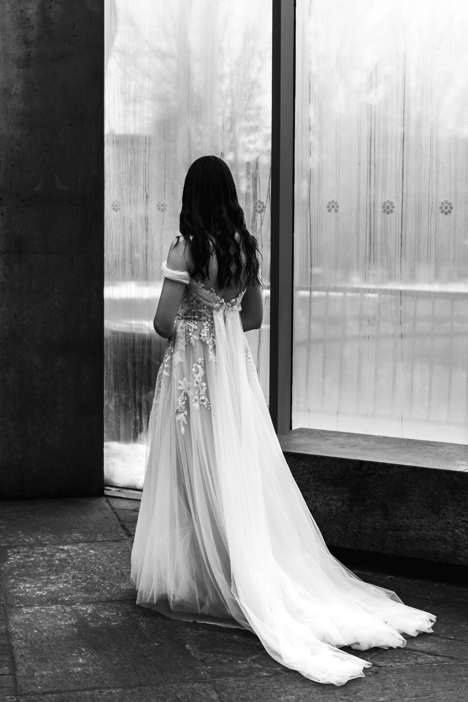 A sequence of black and white photos showing a flowing white wedding dress and veil trailing behind a figure near windows.
