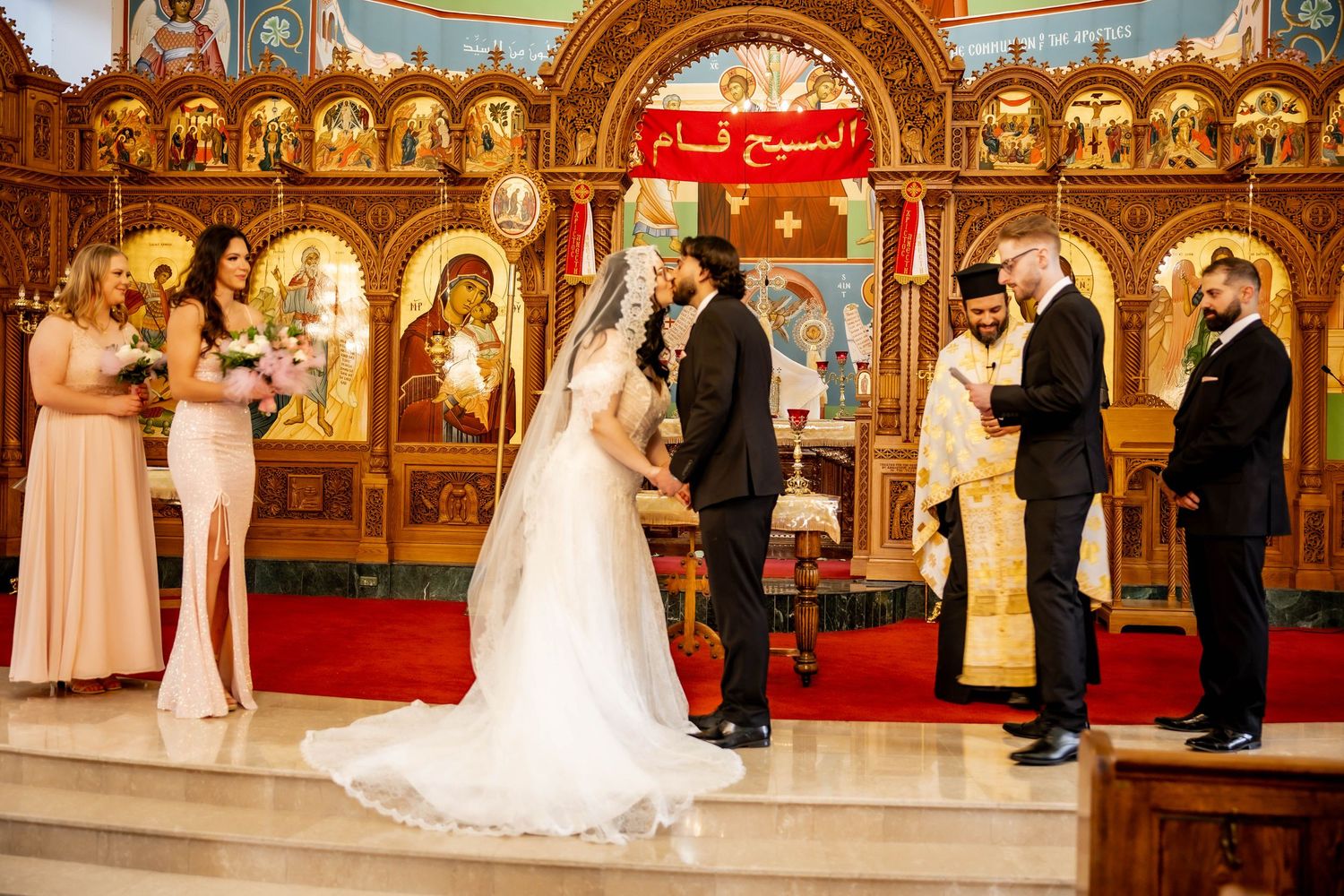 Orthodox church wedding ceremony with ornate gold iconostasis and traditional decorations.