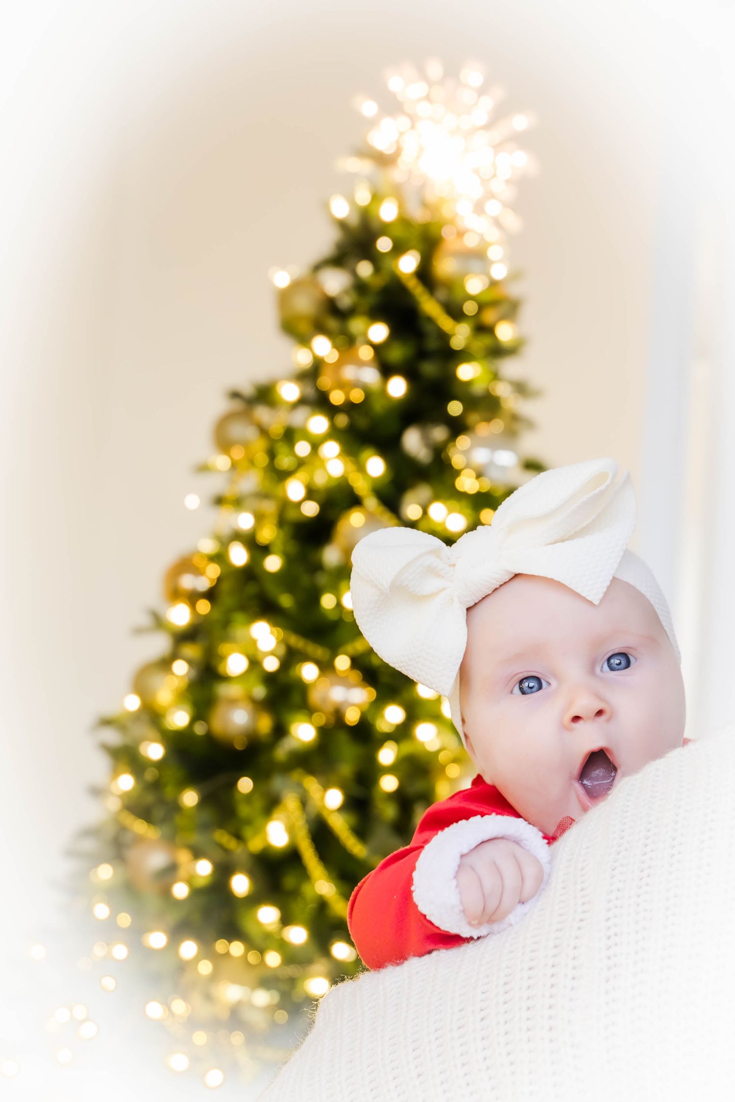 Close-up holiday portrait with Christmas tree lights twinkling in background.