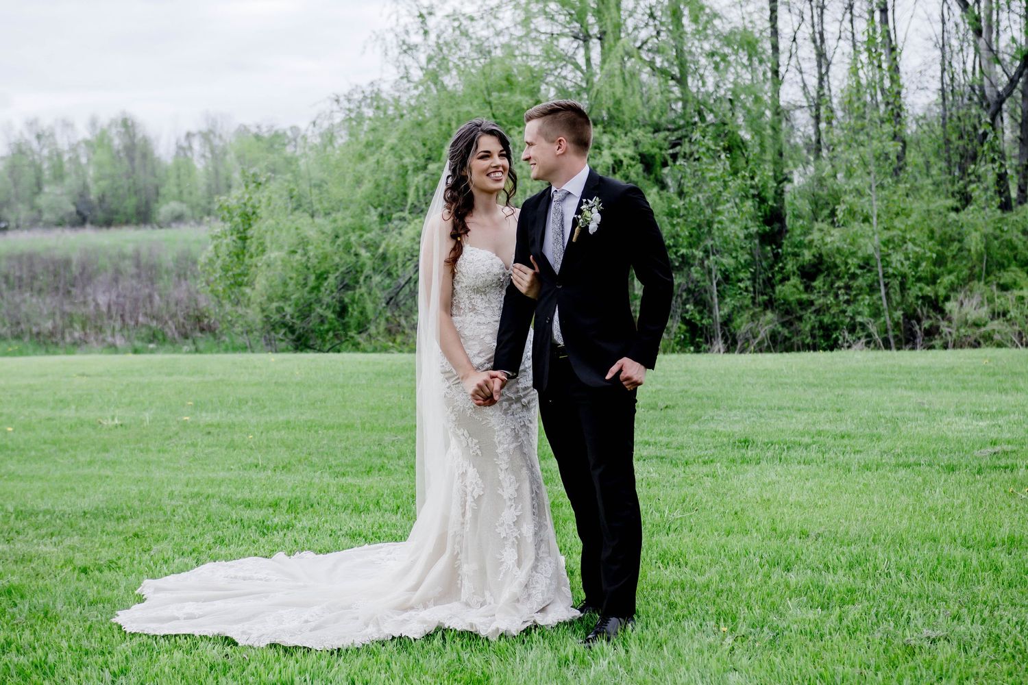 Romantic wedding couple embracing in a lush spring meadow.