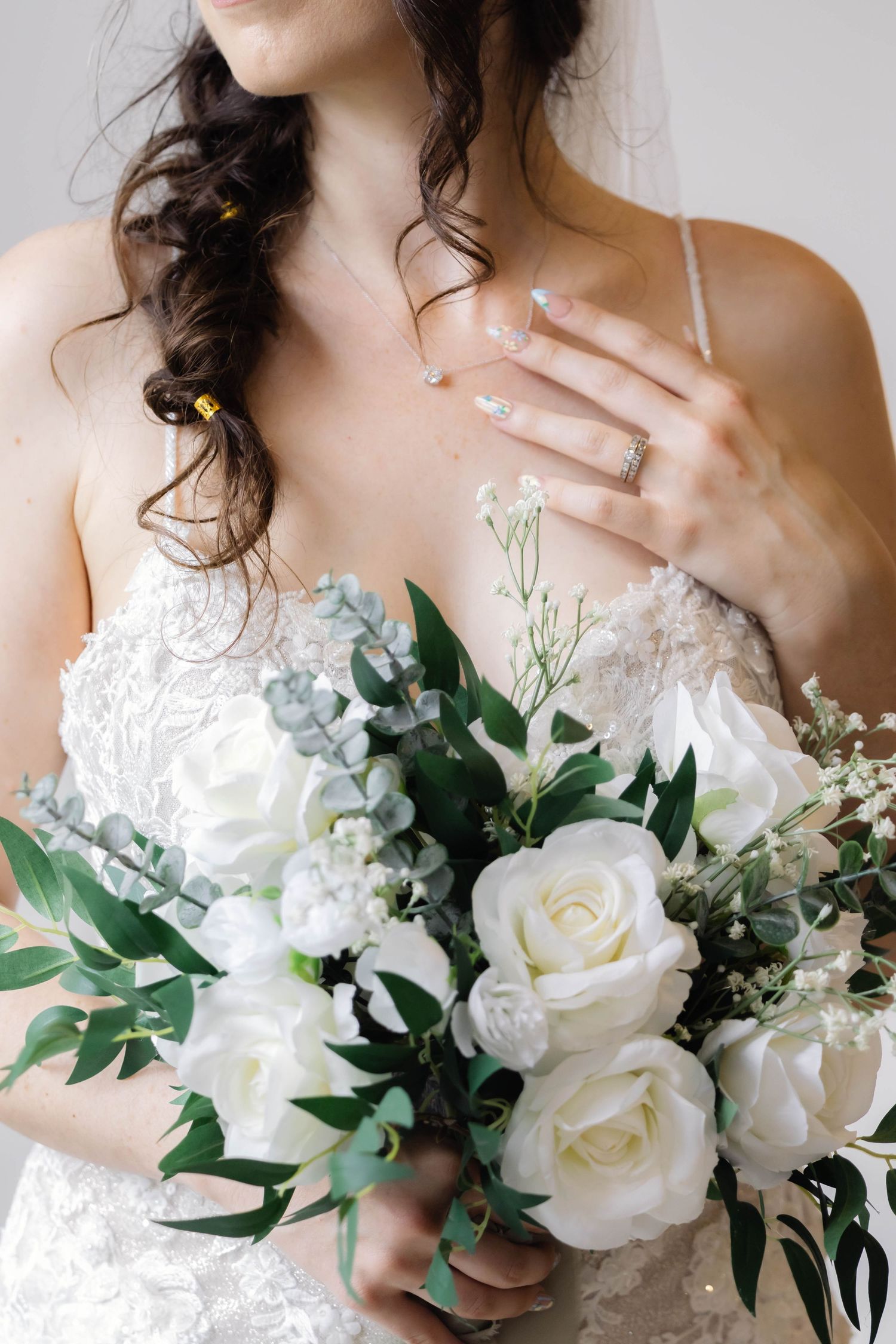 Romantic bridal portrait featuring white rose bouquet and lace wedding dress details.