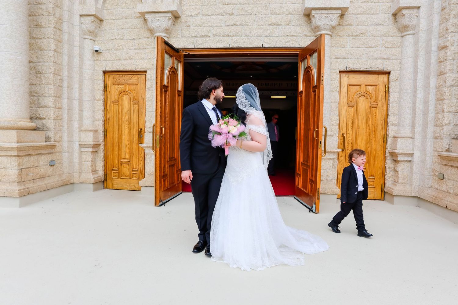 Newlywed couple walks down grand marble steps outside a historic church building after their wedding ceremony.