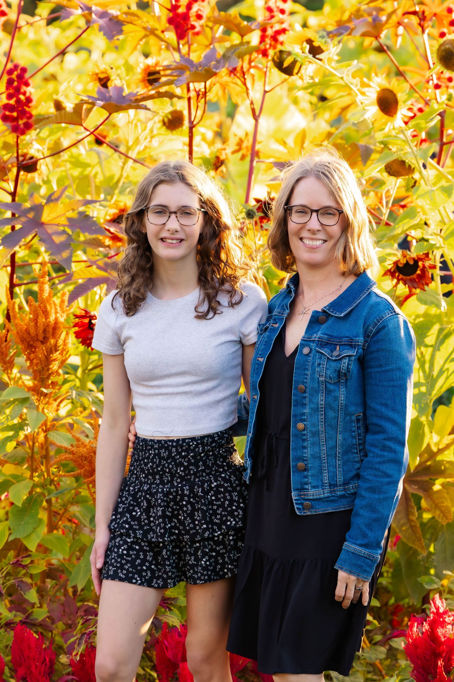 People pose casually together in front of bright yellow fall foliage wearing mixed casual attire.