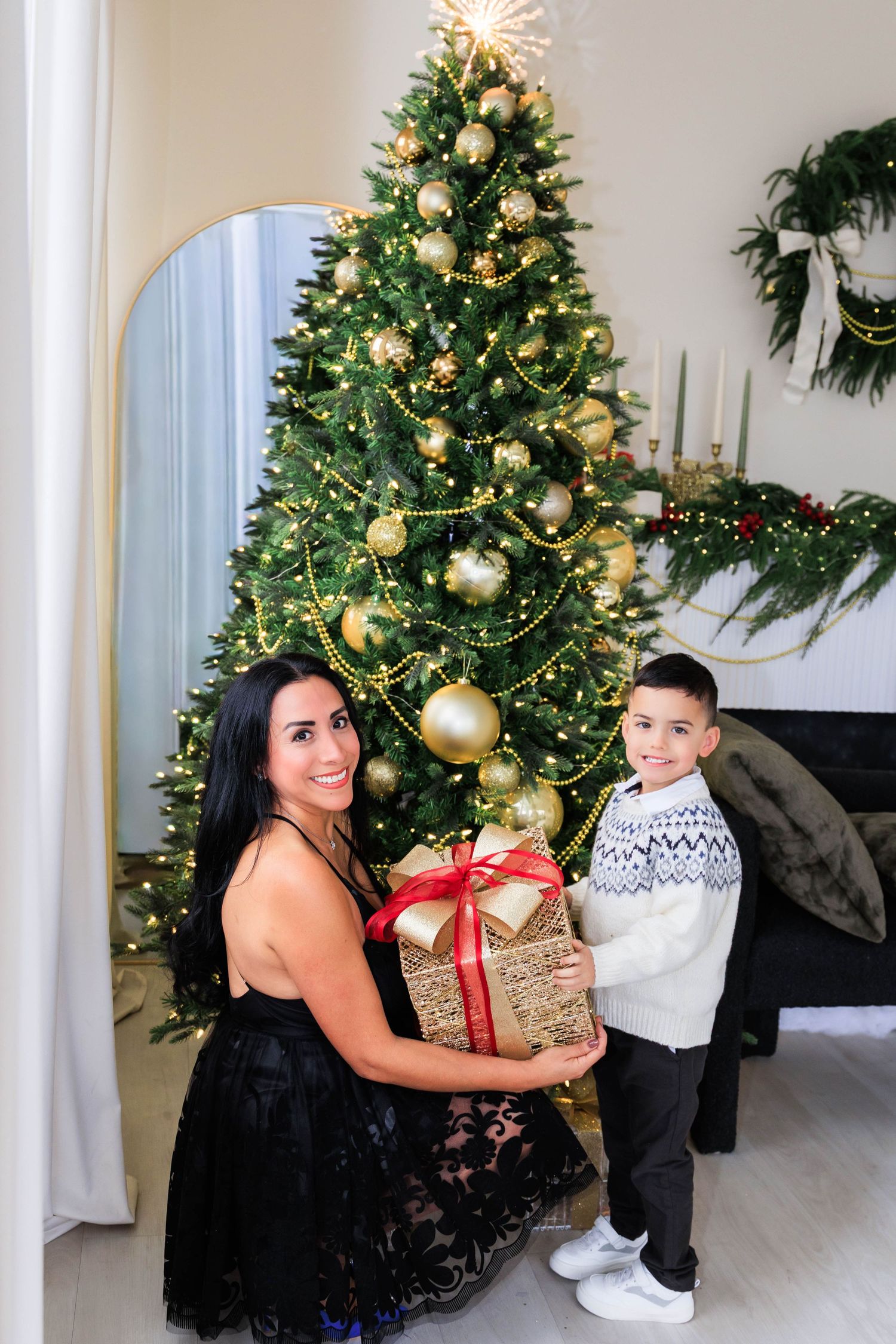 Holiday portraits by elegantly decorated Christmas tree with gold ornaments and white columns.