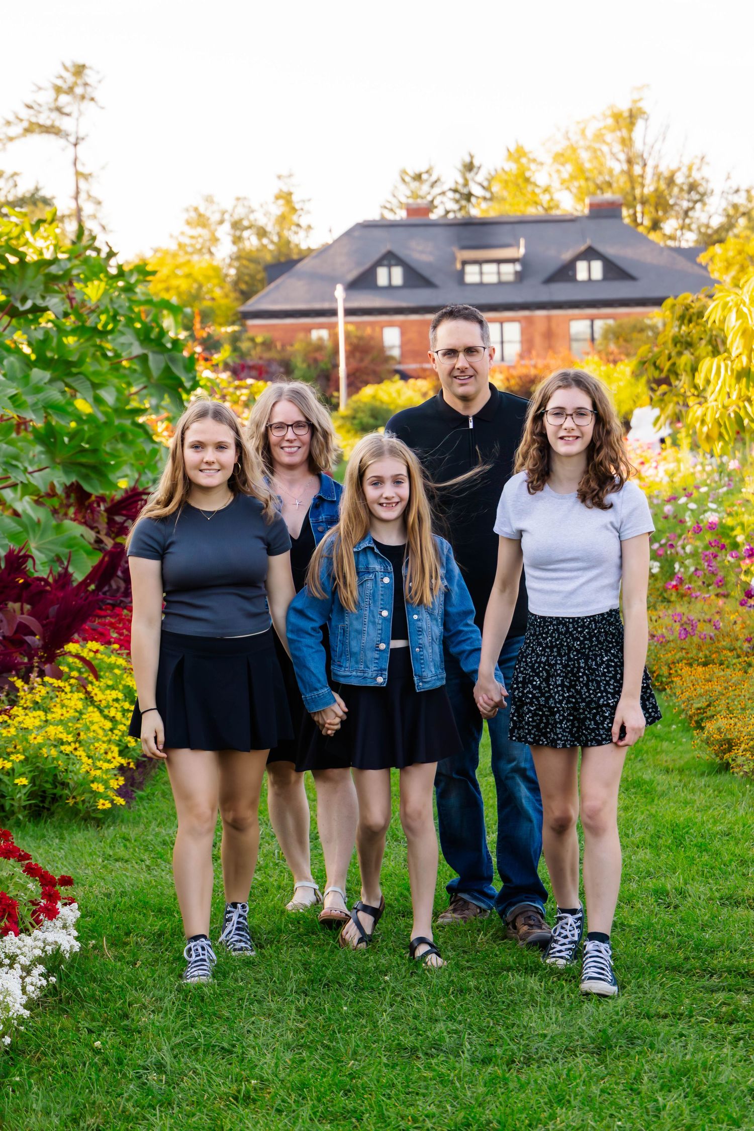 Family portrait session in backyard garden with blooming flowers and greenery.
