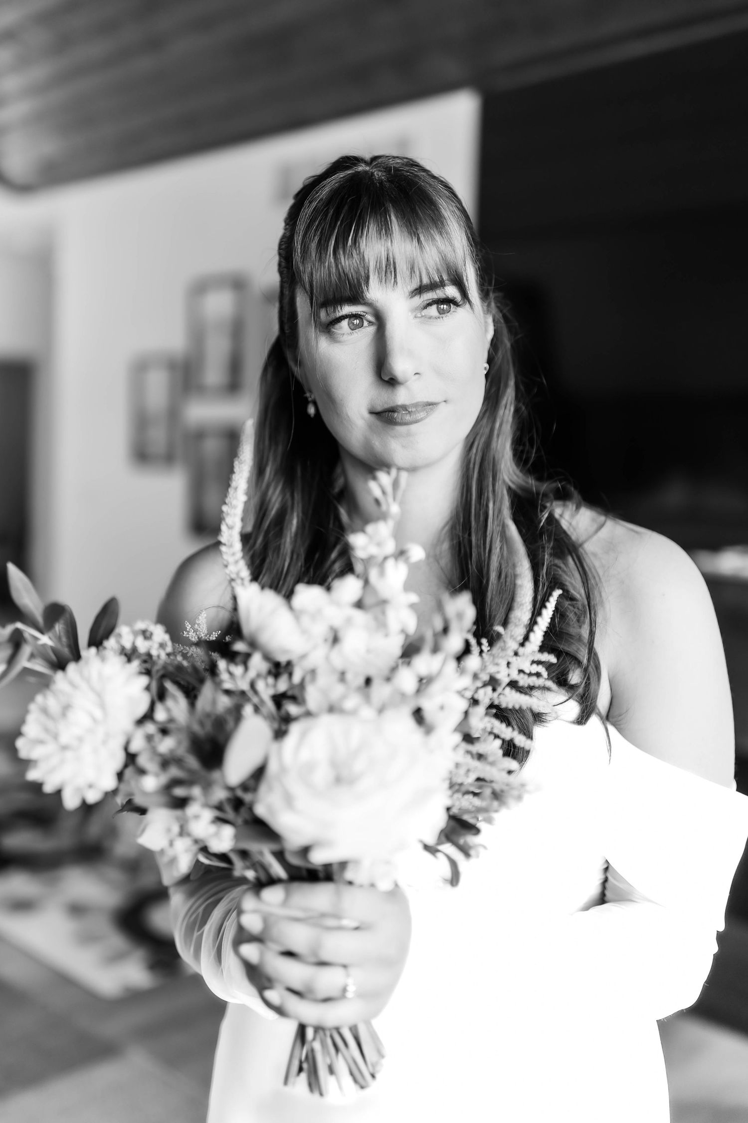 A bride in white holds a delicate bouquet of flowers in a series of black and white portraits.