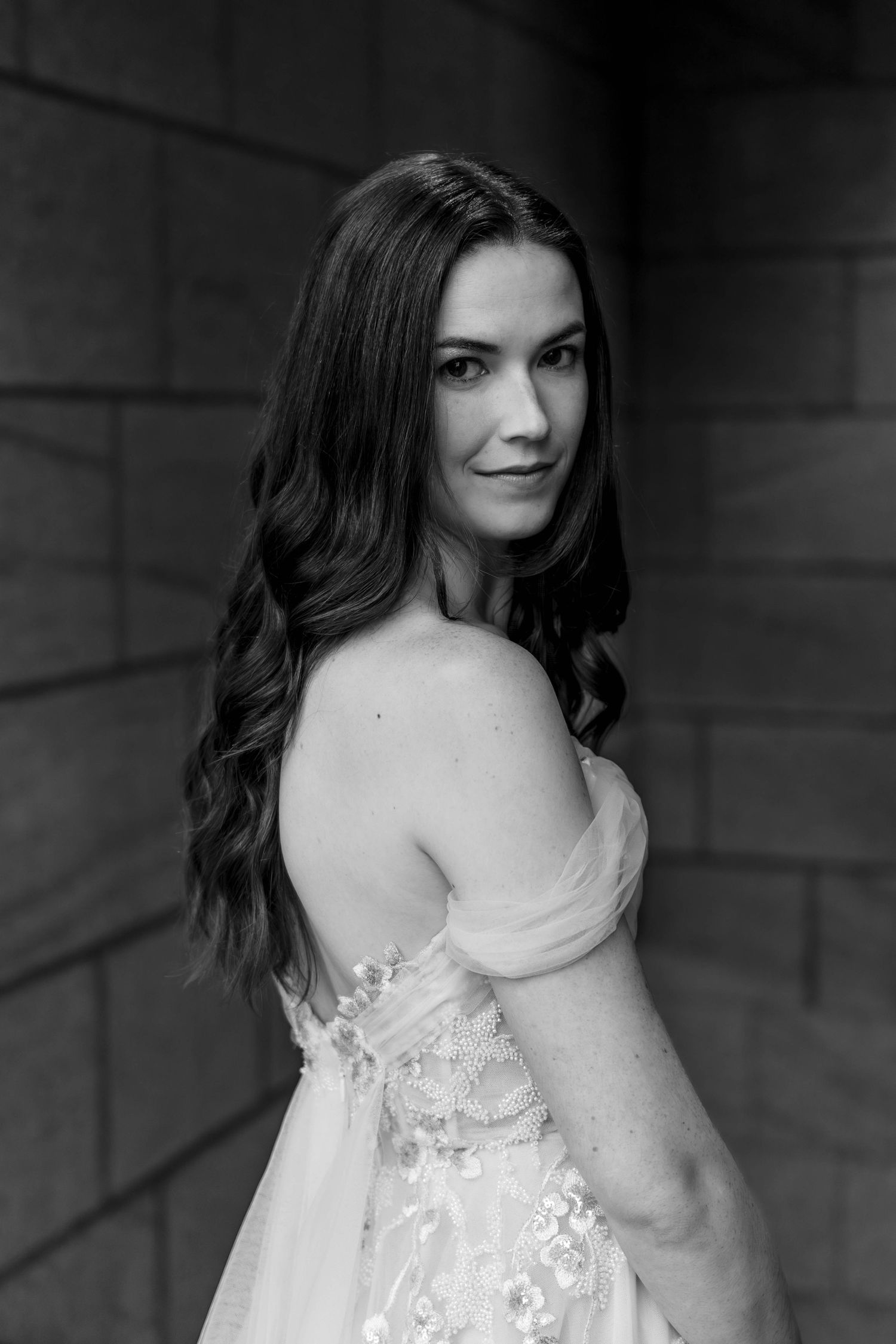 A black and white portrait series showing someone in a delicate white lace dress against a dark background.