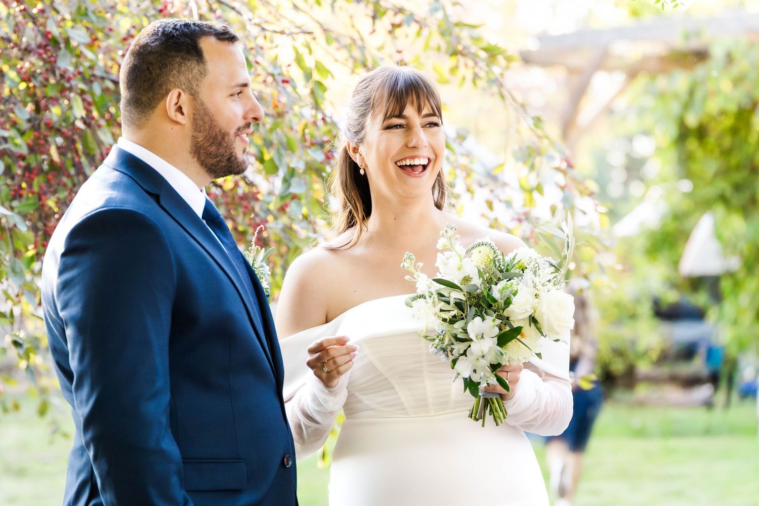 A joyful wedding couple shares intimate moments outdoors in a garden setting during their special day.